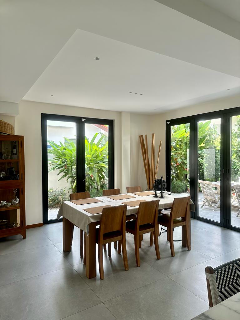 How I plan and organise my kitchen - Modern dining room with wooden chairs and a long table, large glass sliding doors