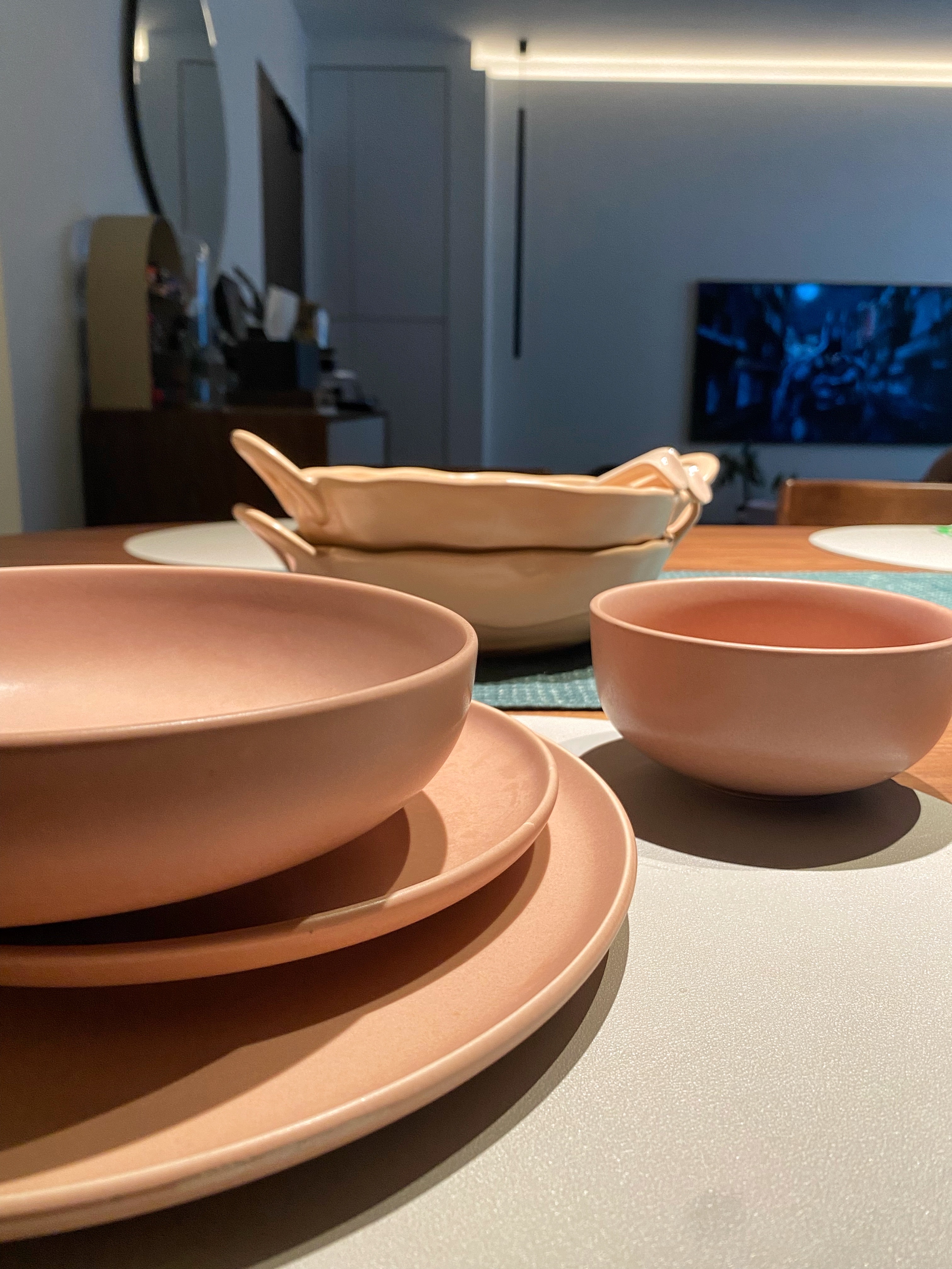 It all started with the color of the sofa...  - Muted terracotta bowls, modern dining table, minimalist decor, soft lighting