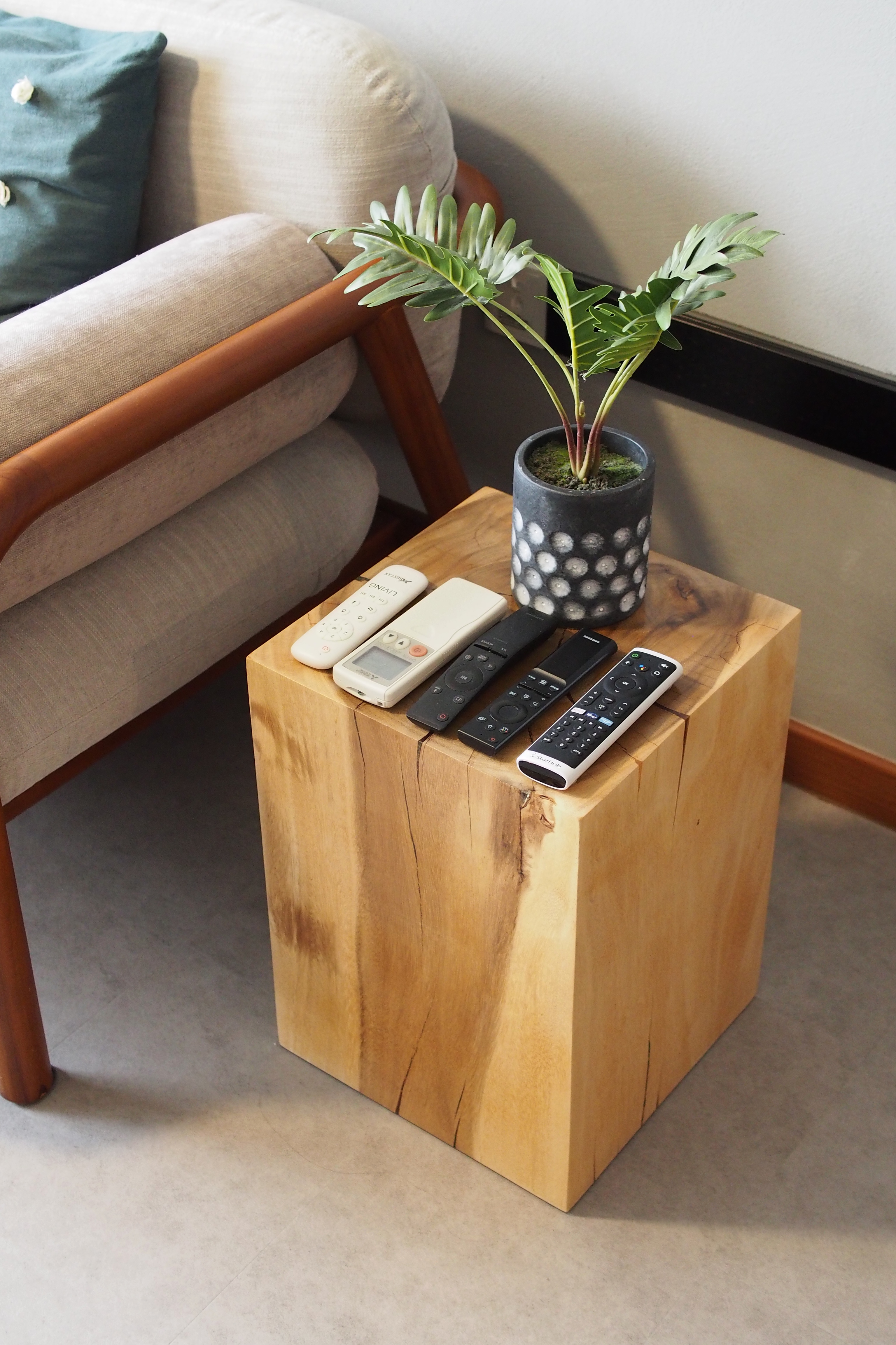 Styling a living room with 0 built-ins - Wooden coffee table, remote controls, modern decor, beige sofa, wooden armrests