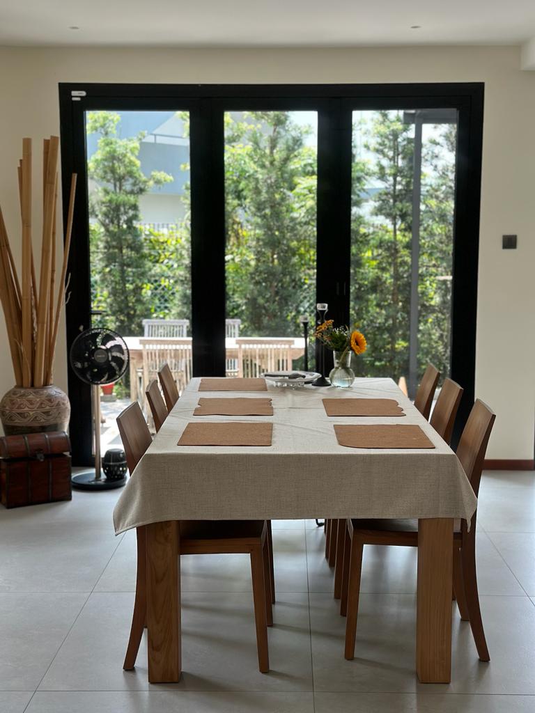 Indoor dining room with an outdoor feel - Large dining table with beige tablecloth, wooden chairs, indoor setting, large
