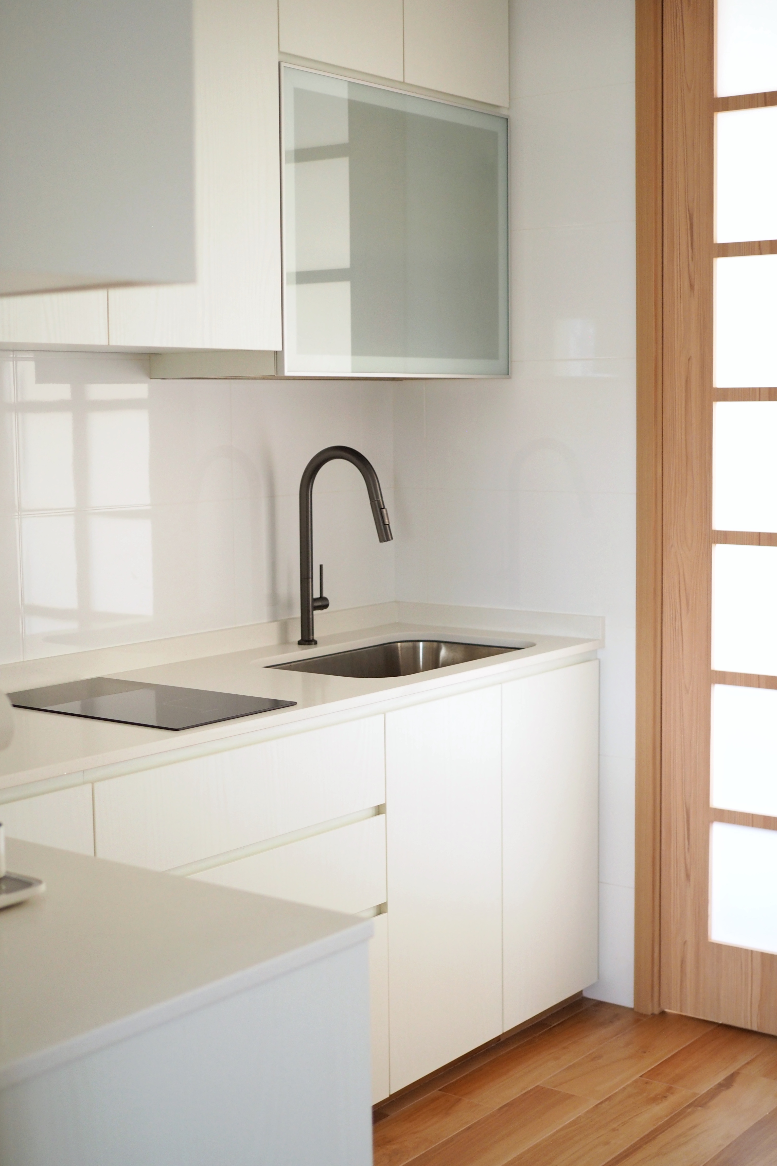 Kitchen for Coffee Lovers - White kitchen cabinetry, modern sink, black curved faucet, stainless steel sink, wooden floor
