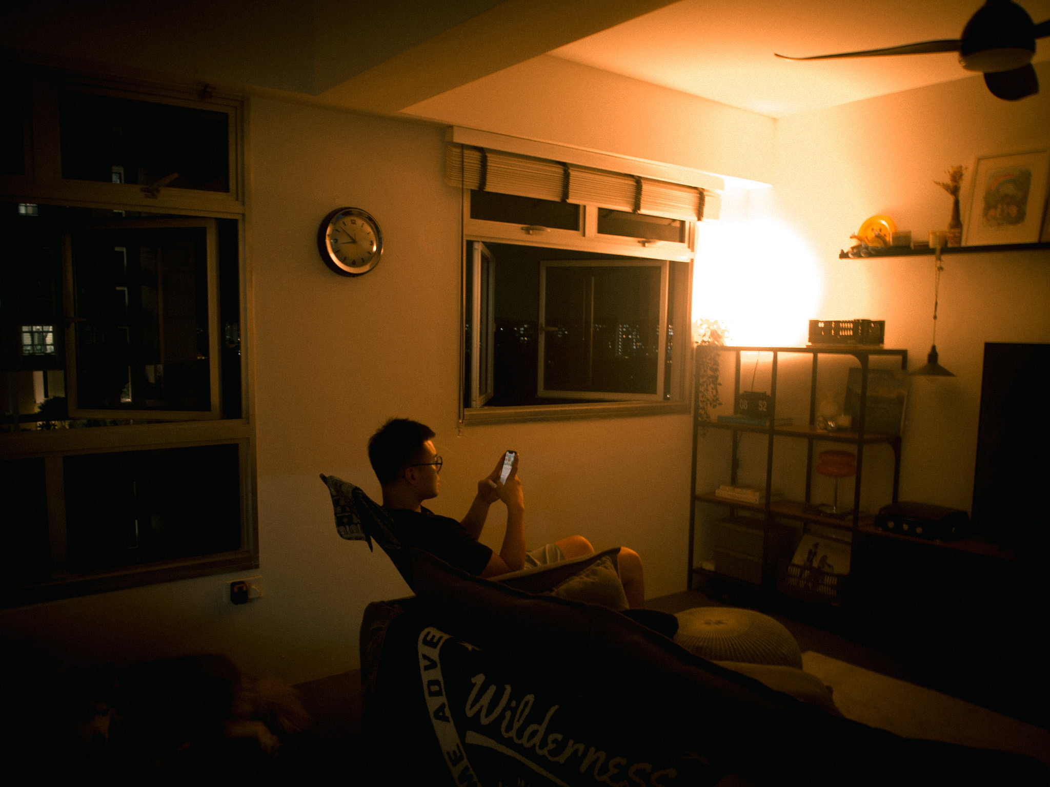 Growing with your Space - living room version - dimly lit room, person sitting, smartphone, indoor setting, window, clock