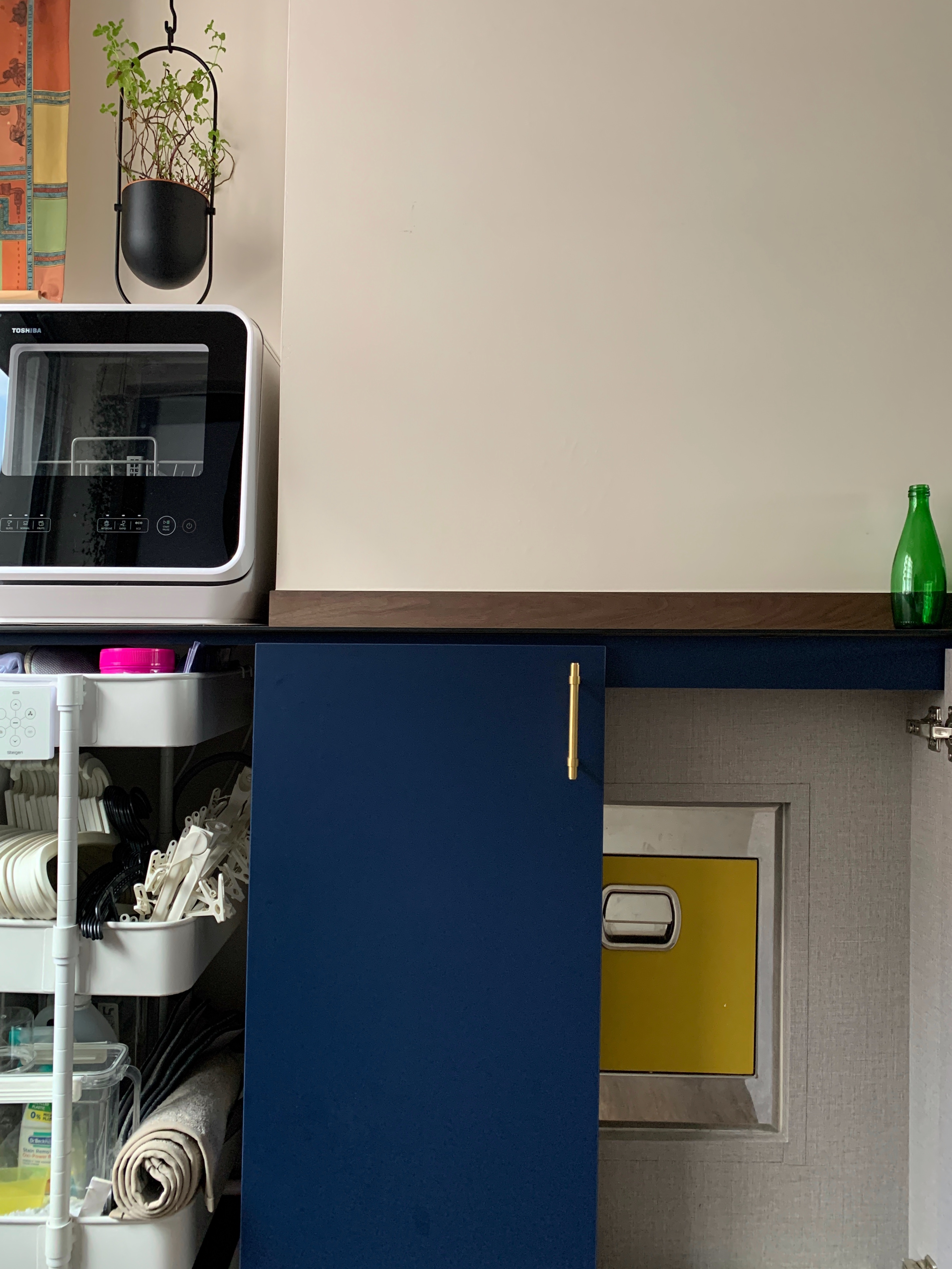 Simple and Clean: A compact laundry space! - microwave, kitchen, countertop, green bottle, blue cabinet, white shelf, plastic