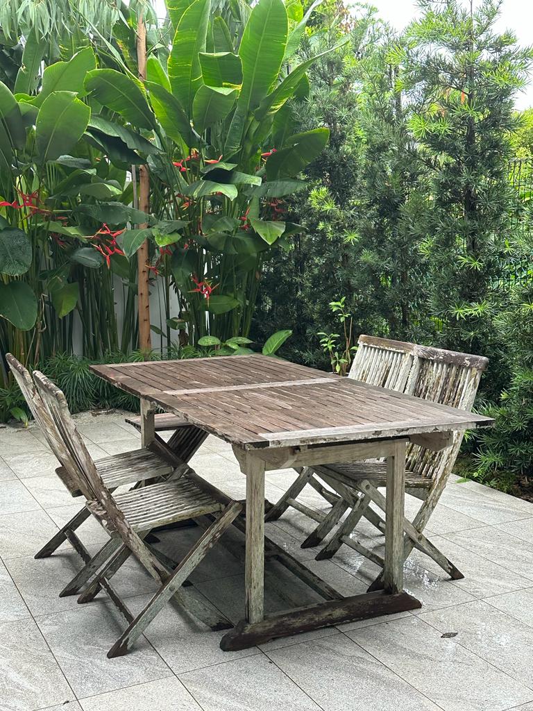 Creating privacy in a dense neighbourhood - Wooden outdoor dining table surrounded by weathered wooden chairs, set on a tiled