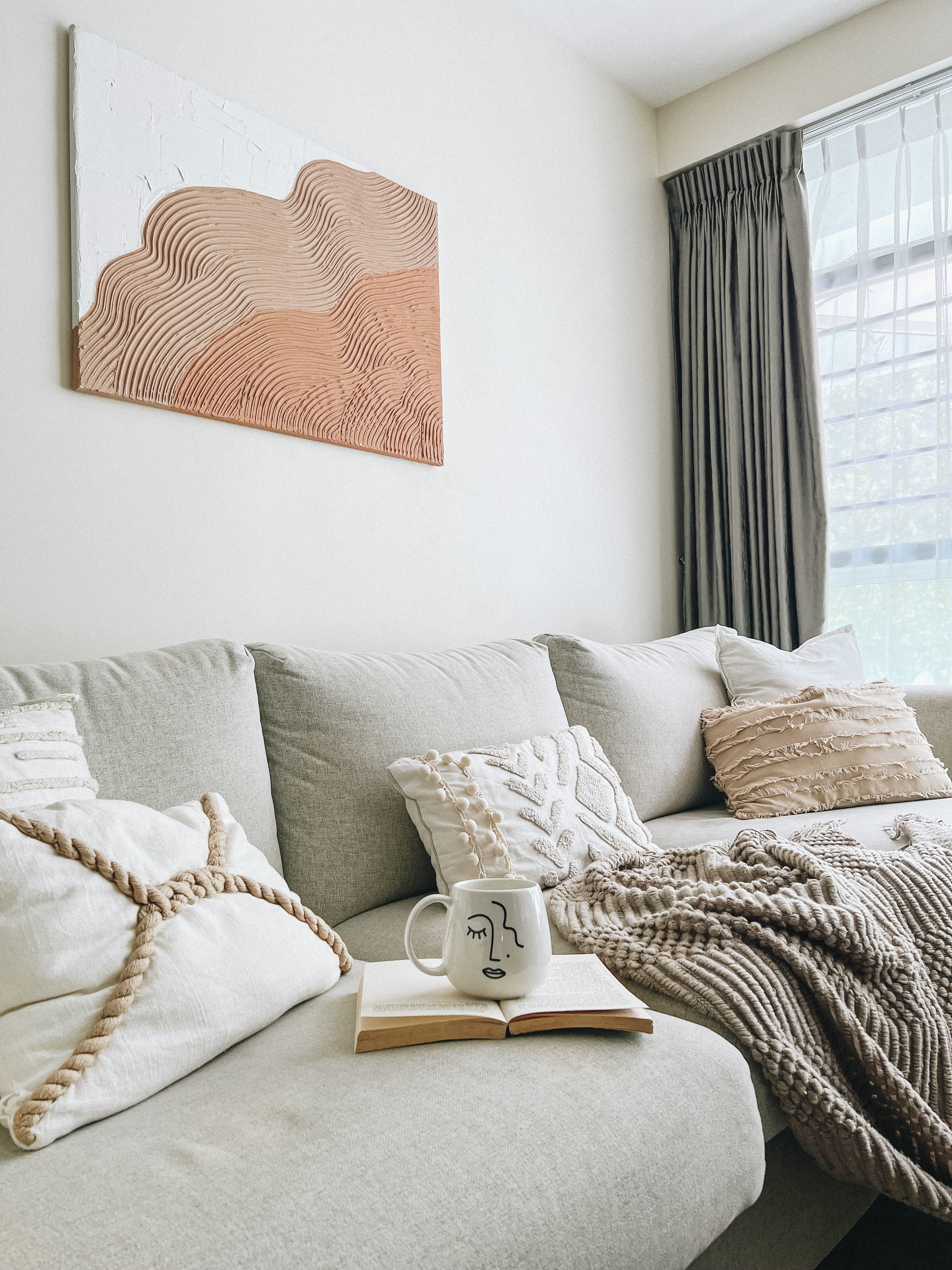 This is where we gather and connect ! - Light gray sofa, textured artwork, cozy cushions, white and beige pillows, knitted