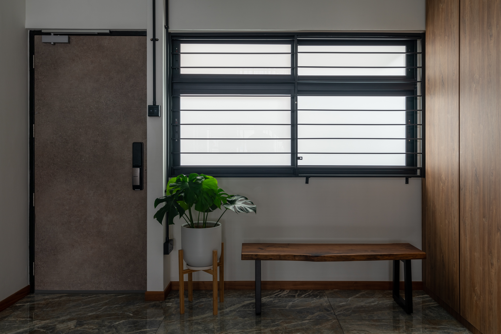 Getting Entry Out of the Way - Modern minimalist interior, closed brown door, white window with black bars, wooden bench