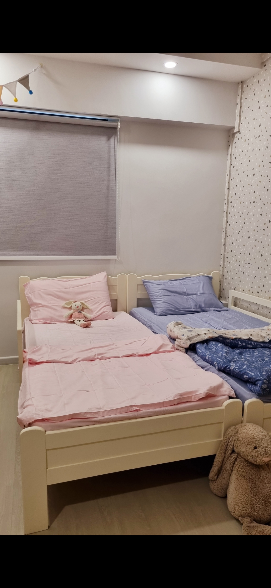 Gender Neutral KIDS bedroom - Soft, pastel-colored bedding, Plush, pink and blue pillows, Wooden headboard with white trim