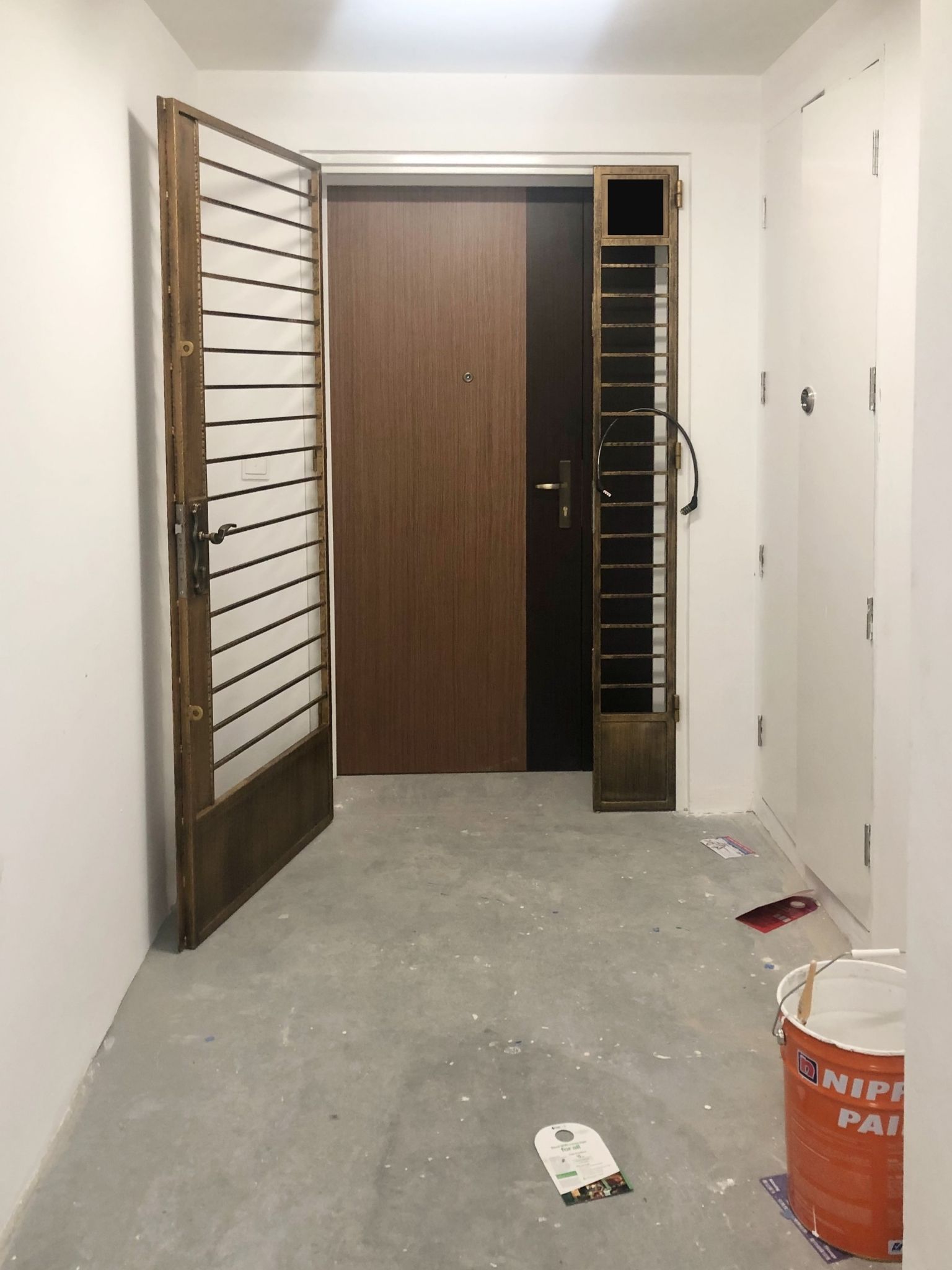 We Spent Below $1K To Transform Our BTO Flat Entrance! - Wooden door with metal bars, white walls, unfinished concrete floor