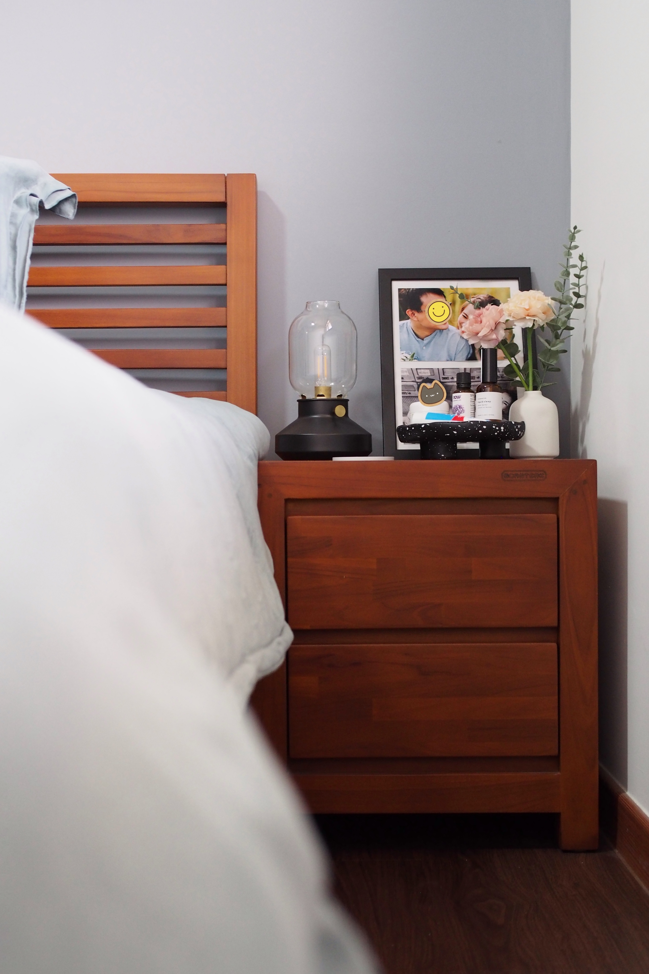King-sized bed with ample space in the MBR? No problem! - Wooden nightstand, bedside table, framed photo, white flowers