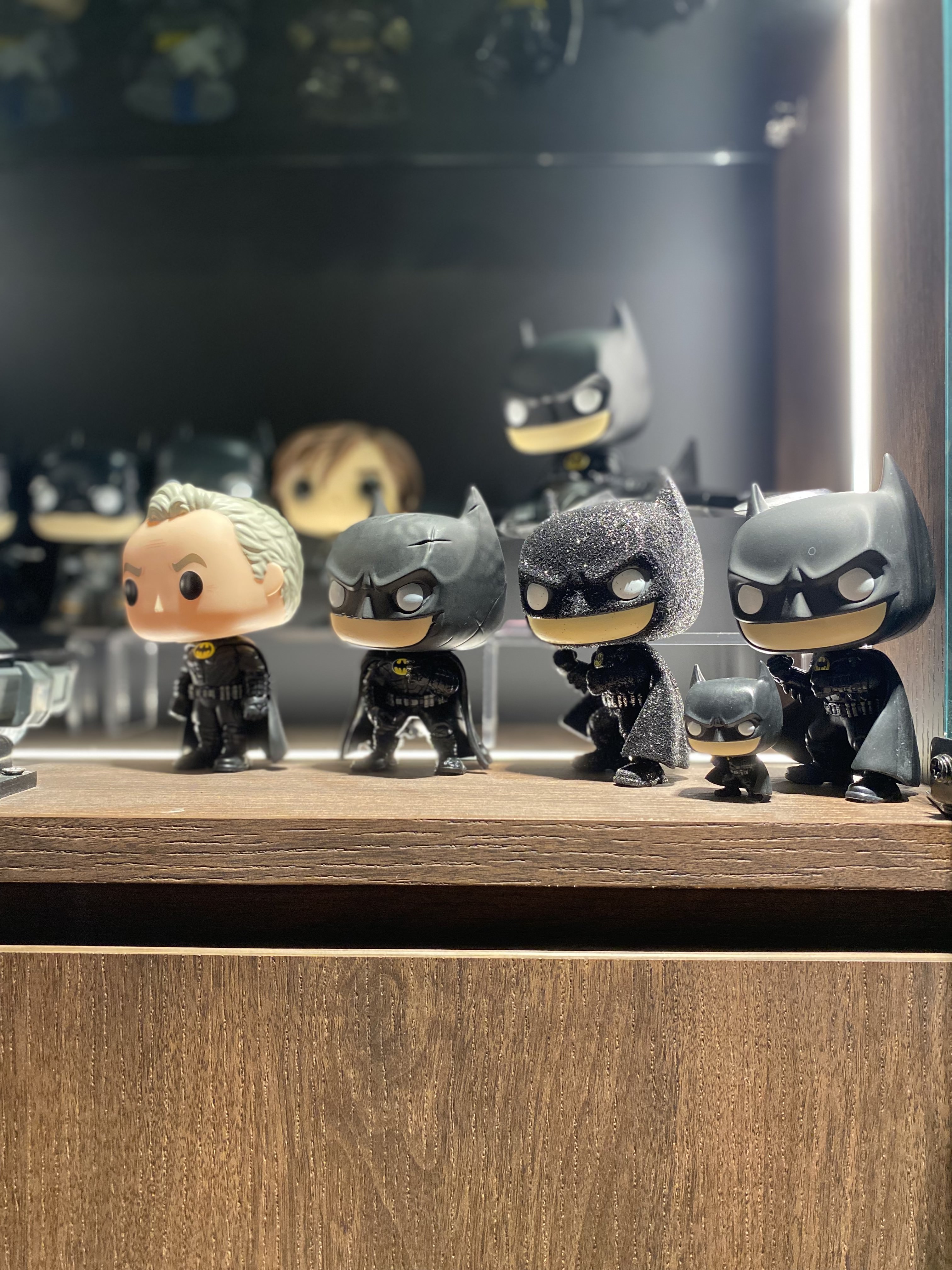 Masterpiece: Showcasing the showcase that showcases our showcase - Batman figurines on wooden shelf, Dark-themed Batman