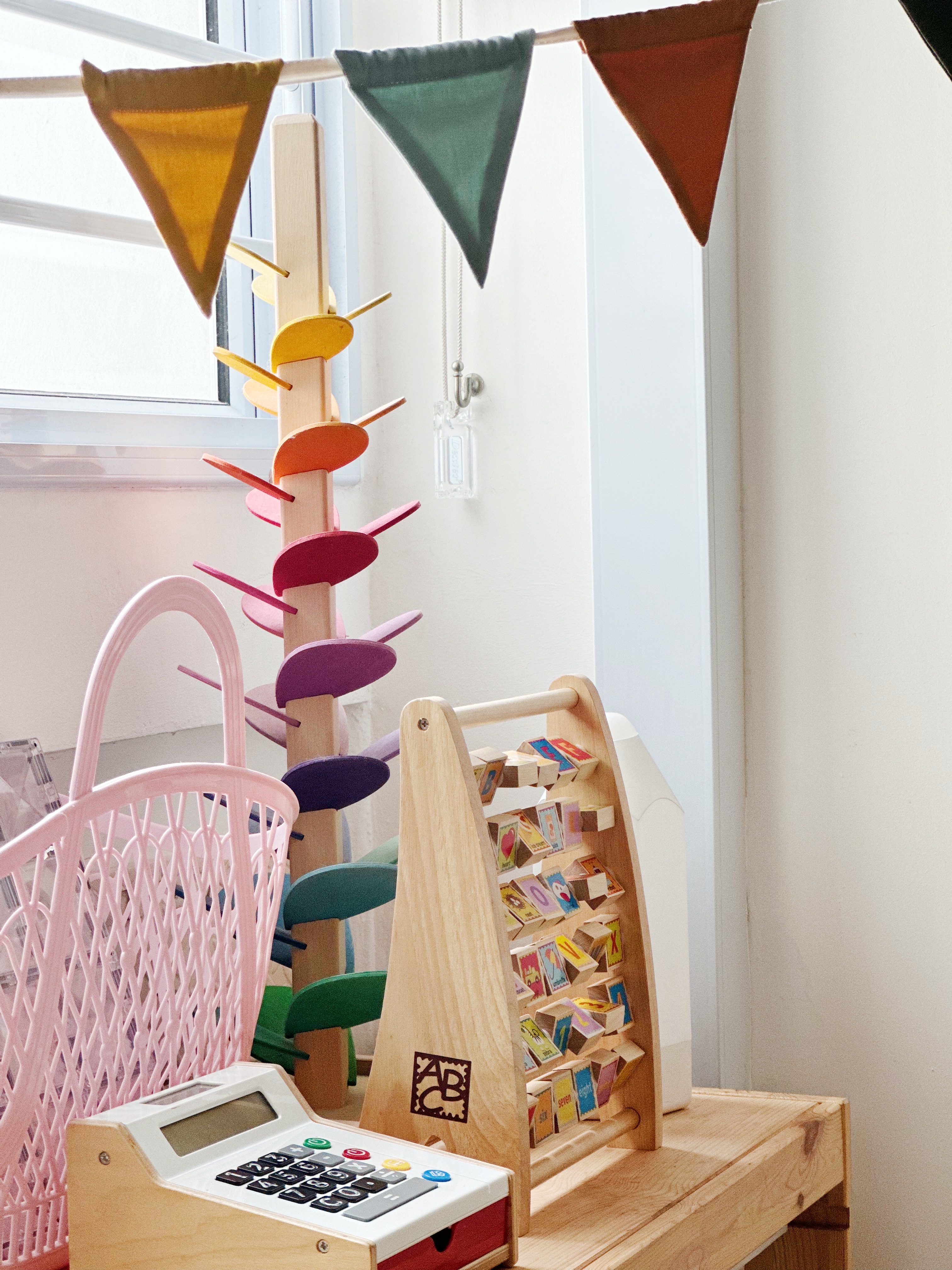 Playroom / Bedroom - Children's playroom, colorful triangular flags, wooden toy structure, pink basket, wooden toy stand