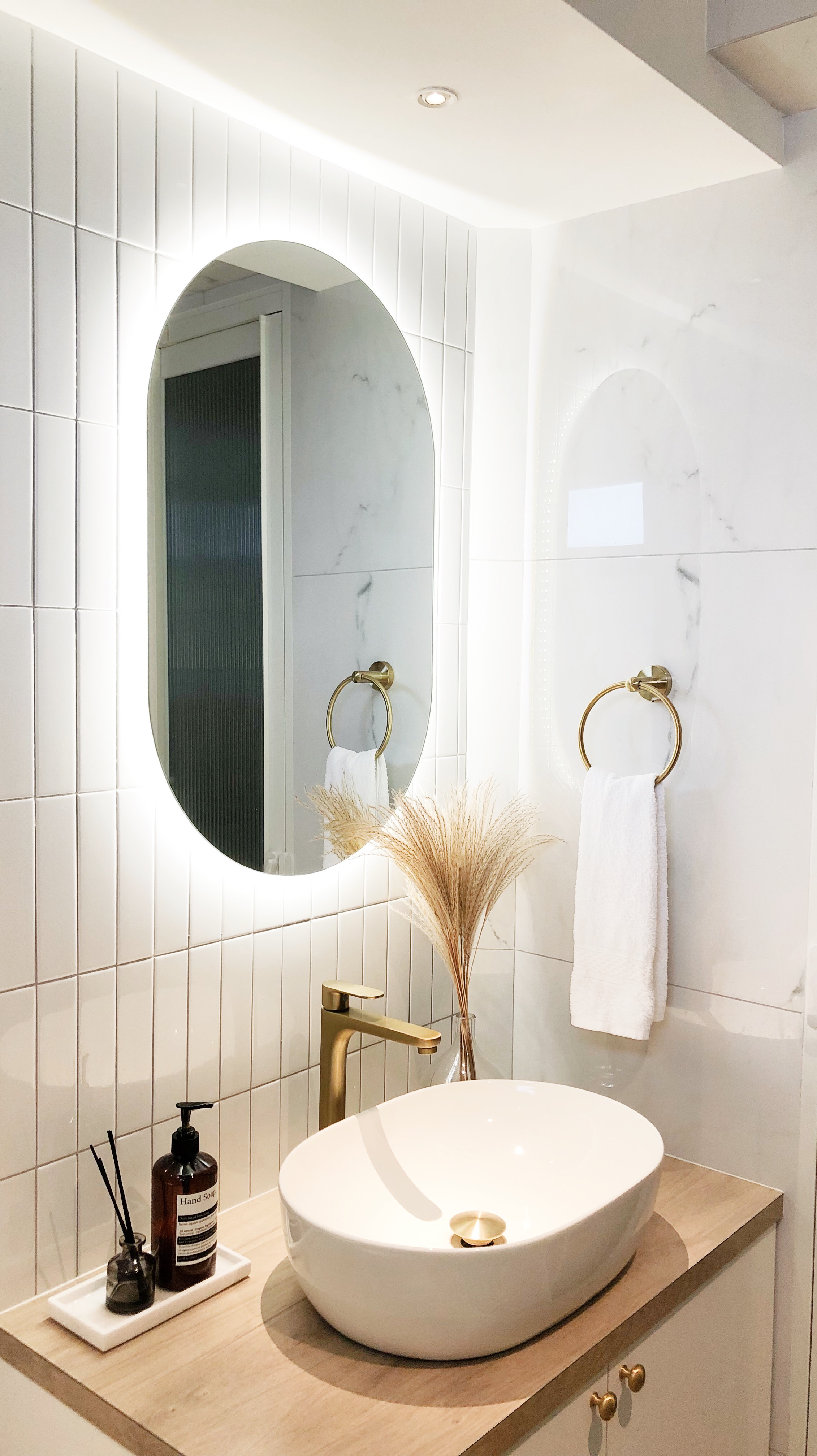 How To Get That Inviting & Luxurious Bathroom Look! - White tiled bathroom, modern design, oval mirror, gold faucet, white