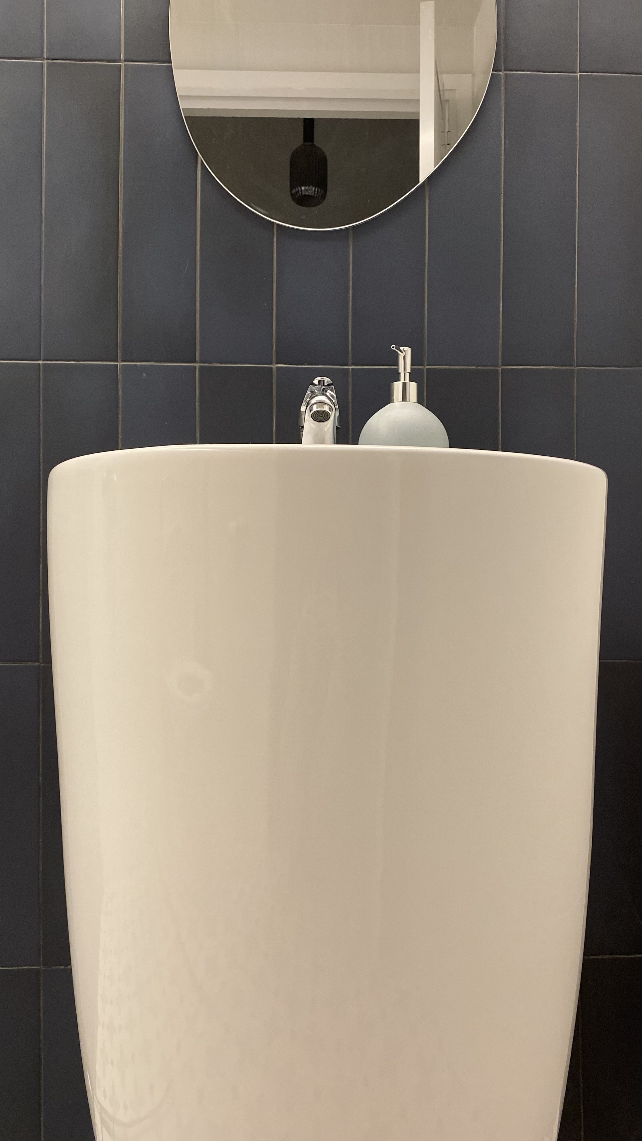 Step into our dwelling - a mixture of styles!  - White oval-shaped sink, dark blue tiled wall, round mirror, silver faucet