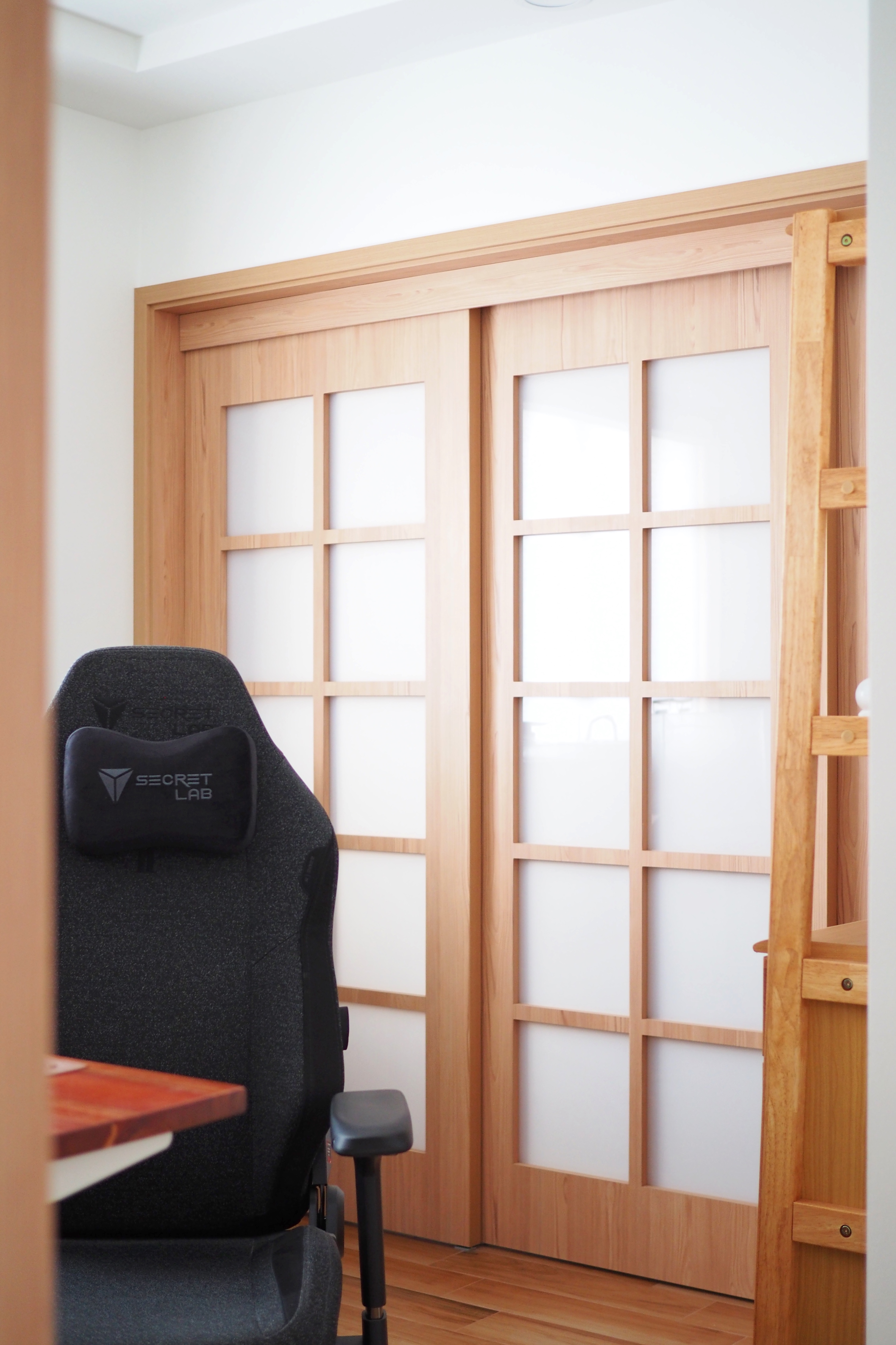 Our Concealable Workspace - Wooden door with glass panels, ergonomic chair labeled "SECRET LAB, " modern interior design