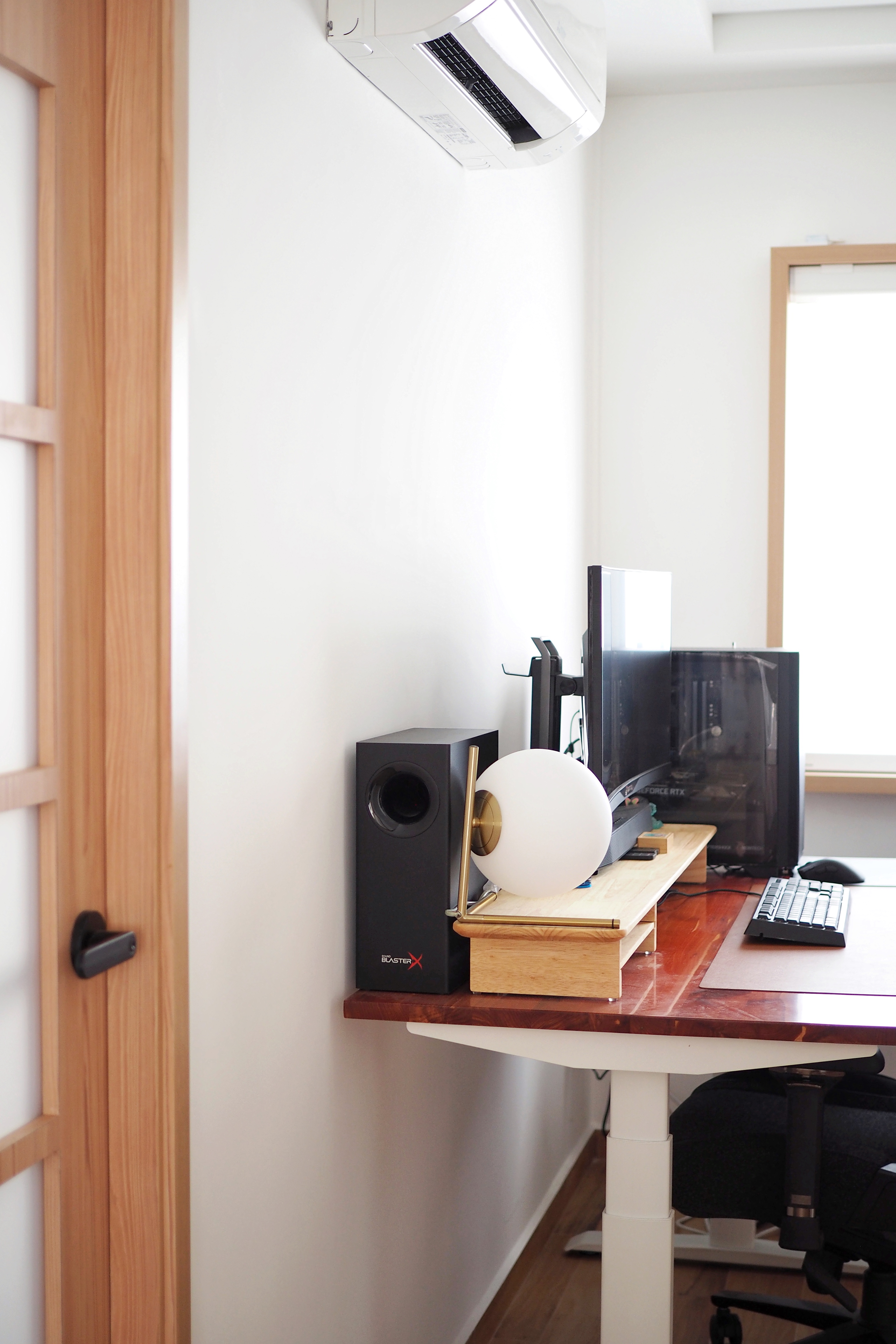 Our Concealable Workspace - Wooden desk, black speaker, computer monitor, white spherical object, black computer tower