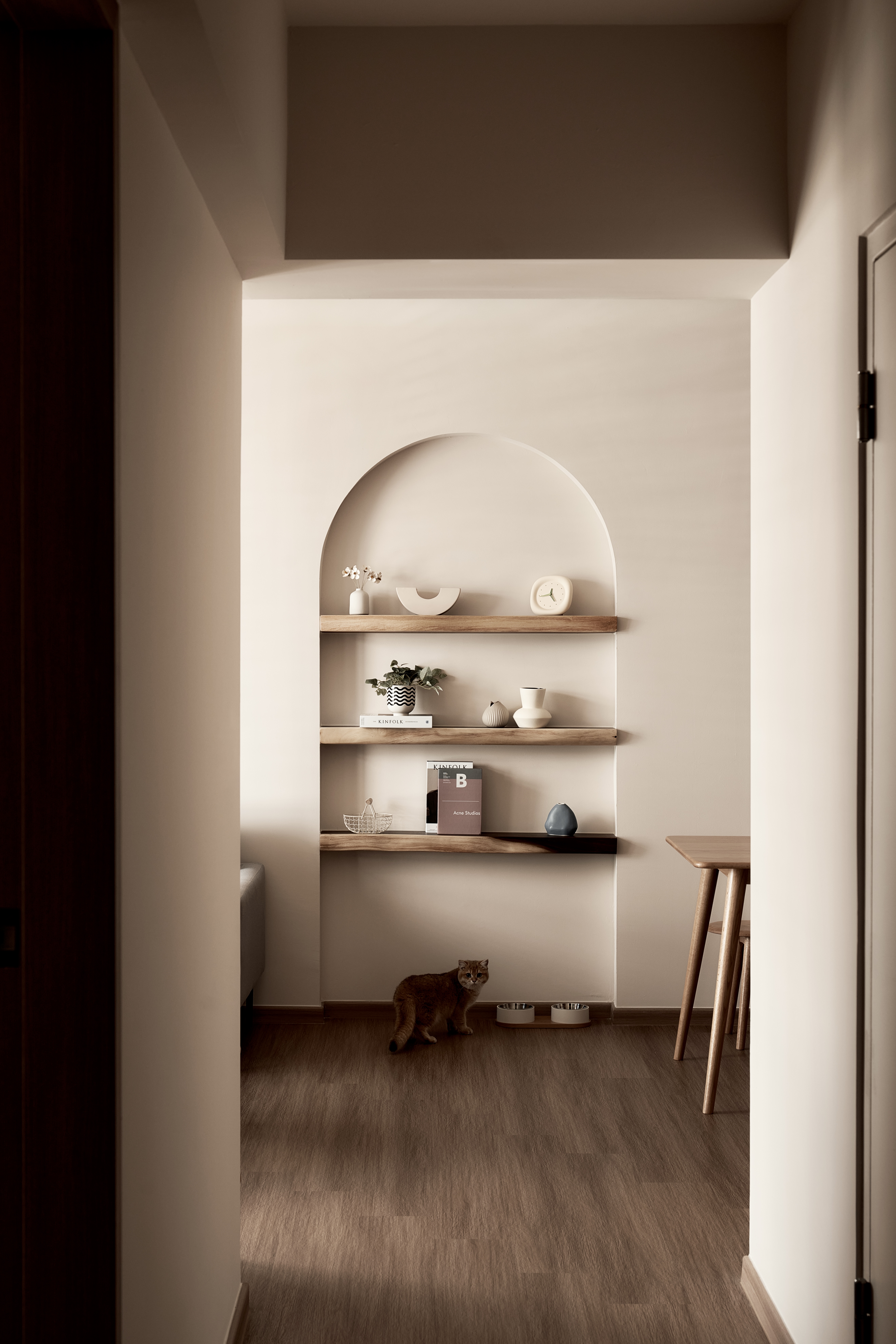 Curves, Wood and Greys in Living Room  - Wooden shelves, minimalist decor, arched alcove, soft lighting, modern art, small
