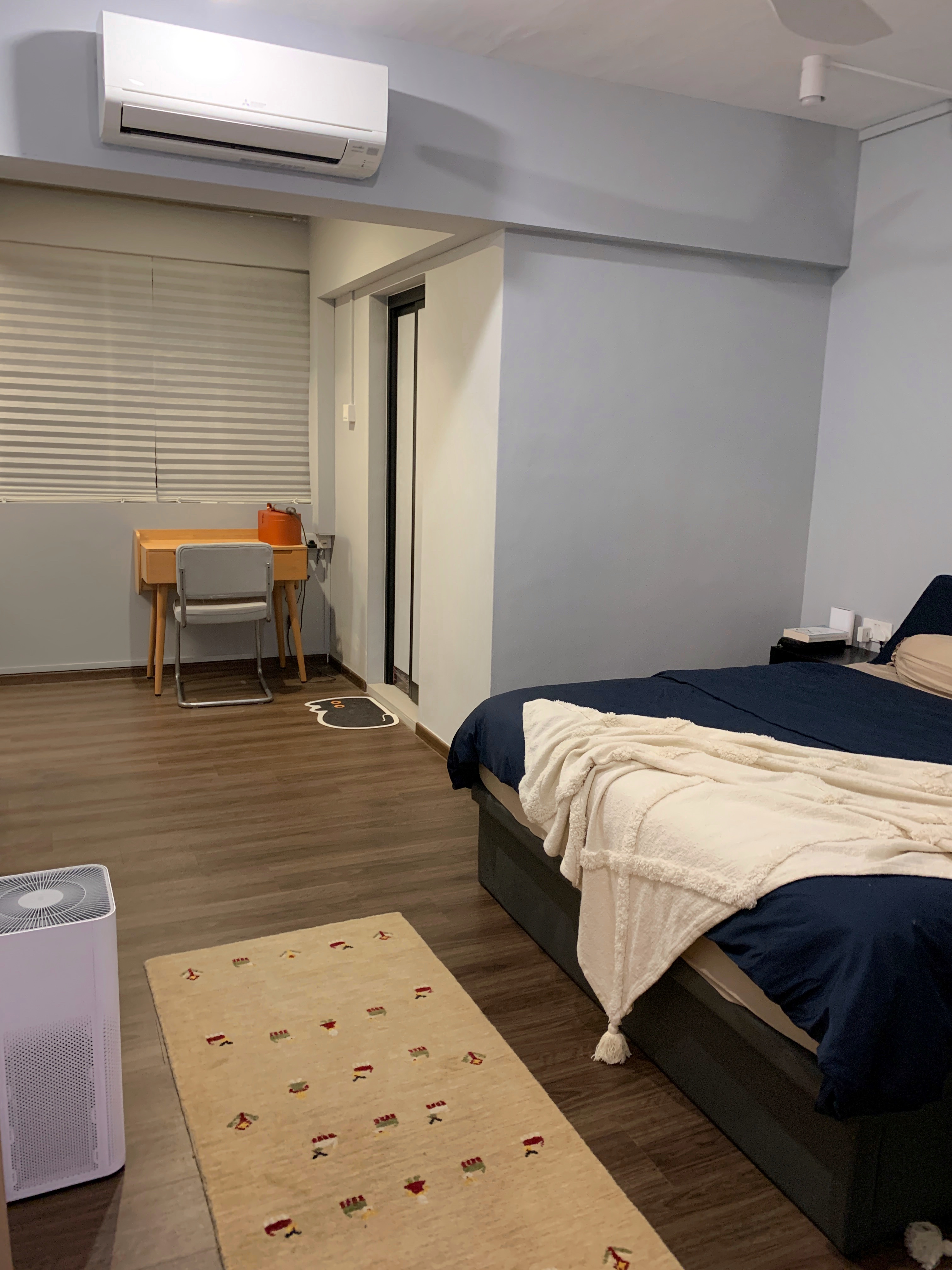 A minimal bedroom with a walk-in wardrobe nook - Modern bedroom with large window, air conditioning unit, wooden desk, chair