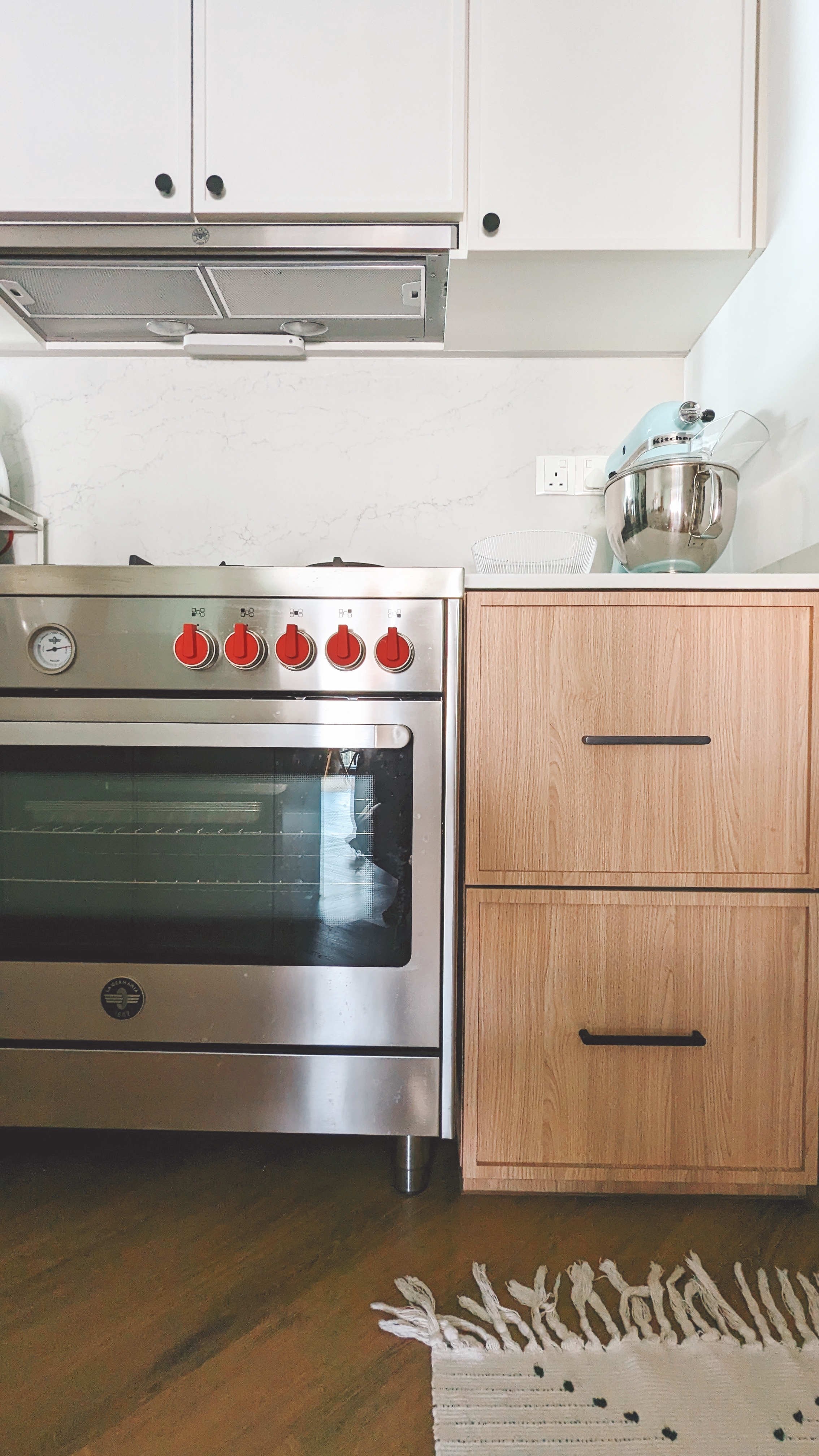 Walk about our quirky, catto-loving space. - Silver oven with red knobs, stainless steel range hood, light wooden cabinets