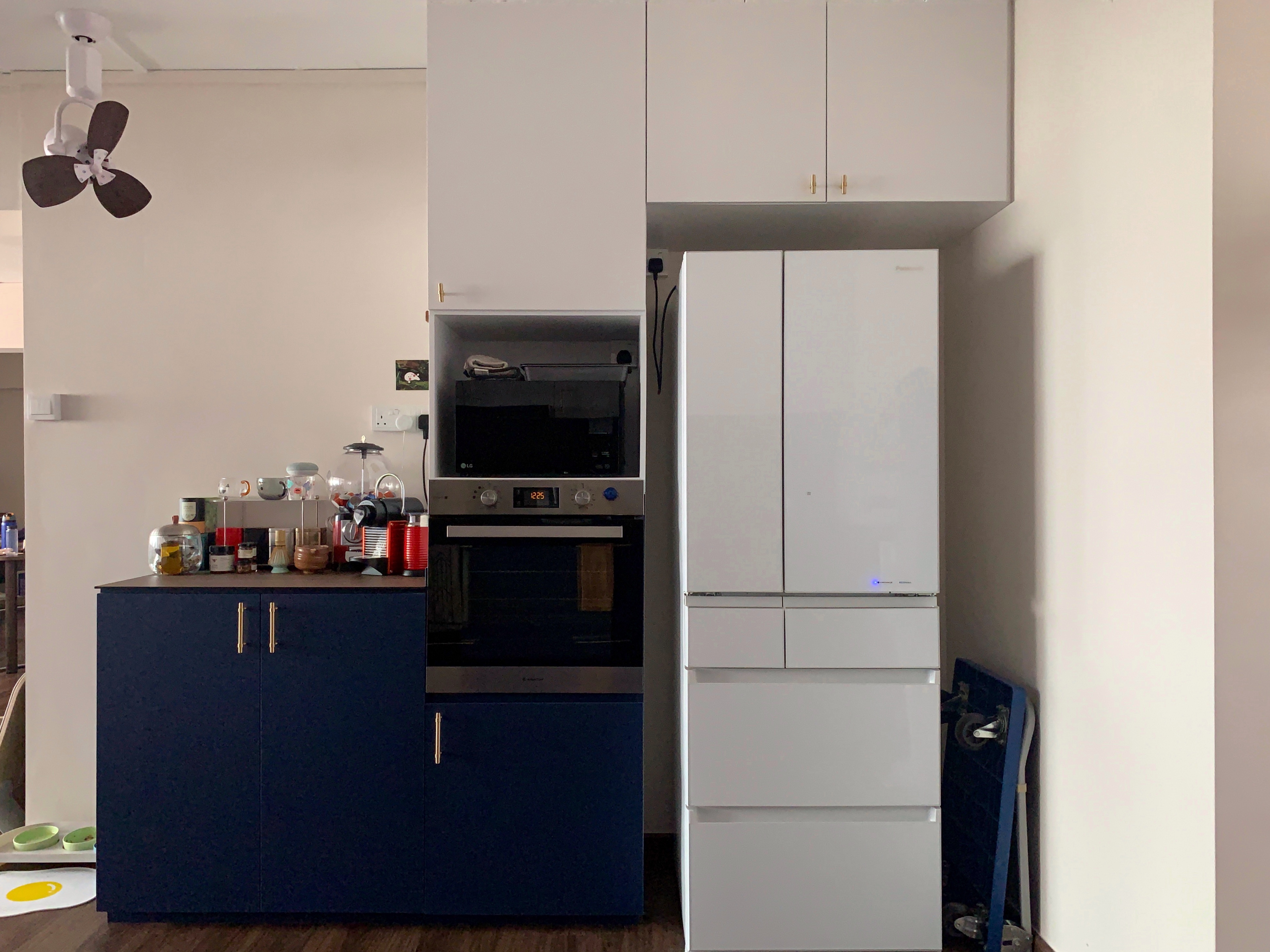 A Spacious Blue and White Contemporary Kitchen - Kitchen island, white refrigerator, blue cabinets, black microwave, white