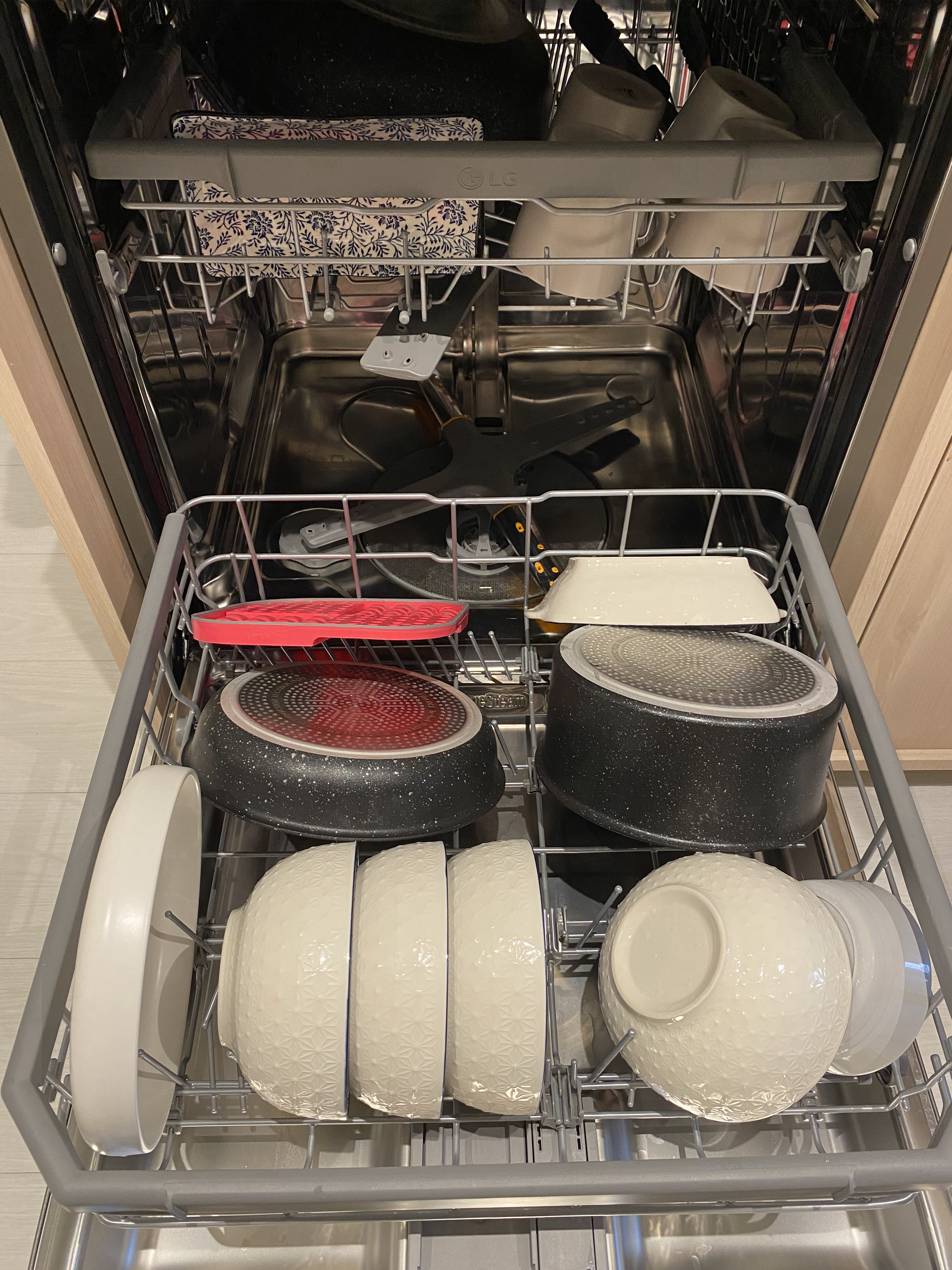 A kitchen meant for hosting - Dishwasher with open door, stainless steel rack, various dishes including plates and bowls, red