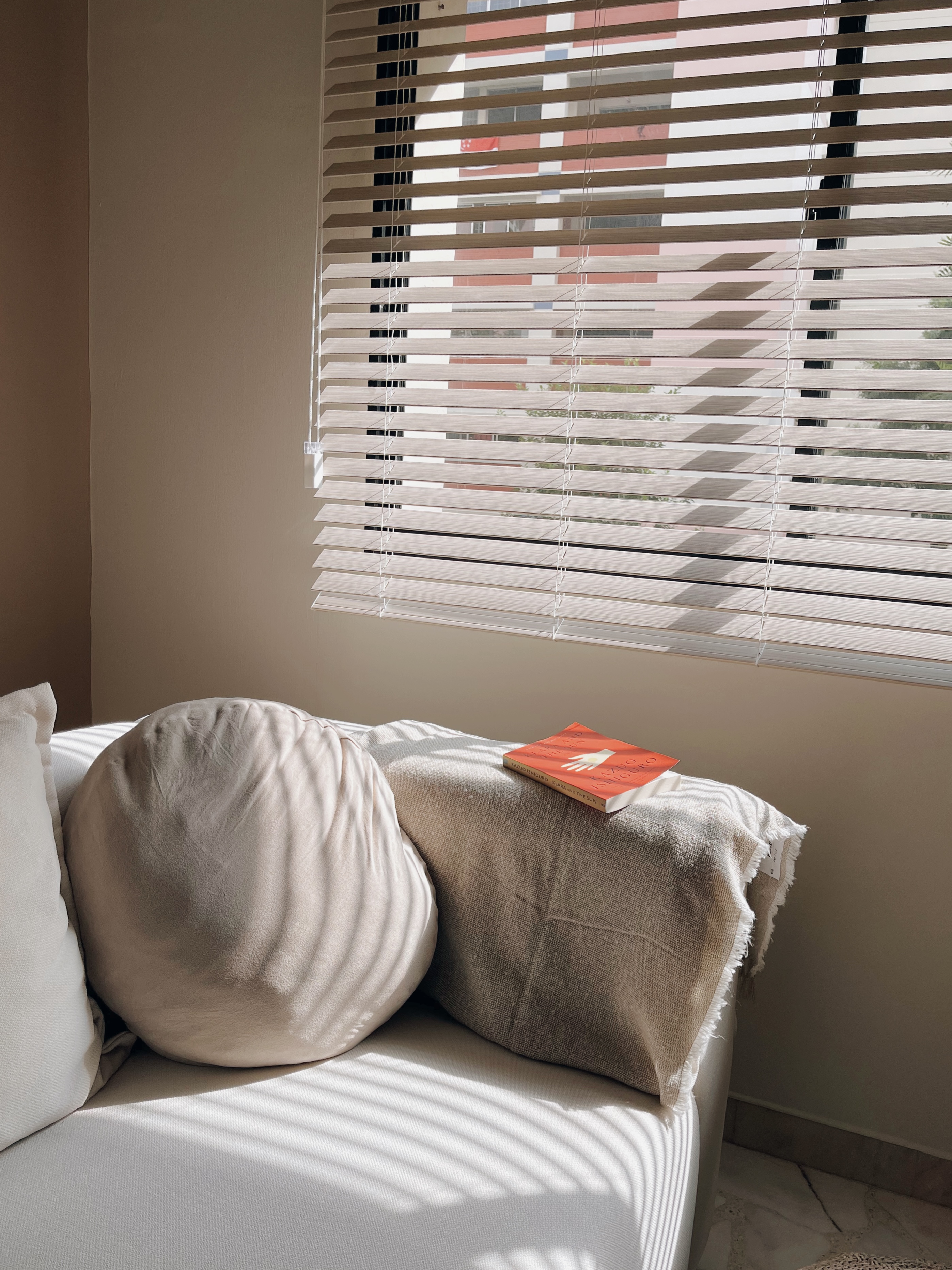 Cosiest nook for me-time and a book! - Sunlight streaming through window, beige blinds partially open, soft shadows cast on
