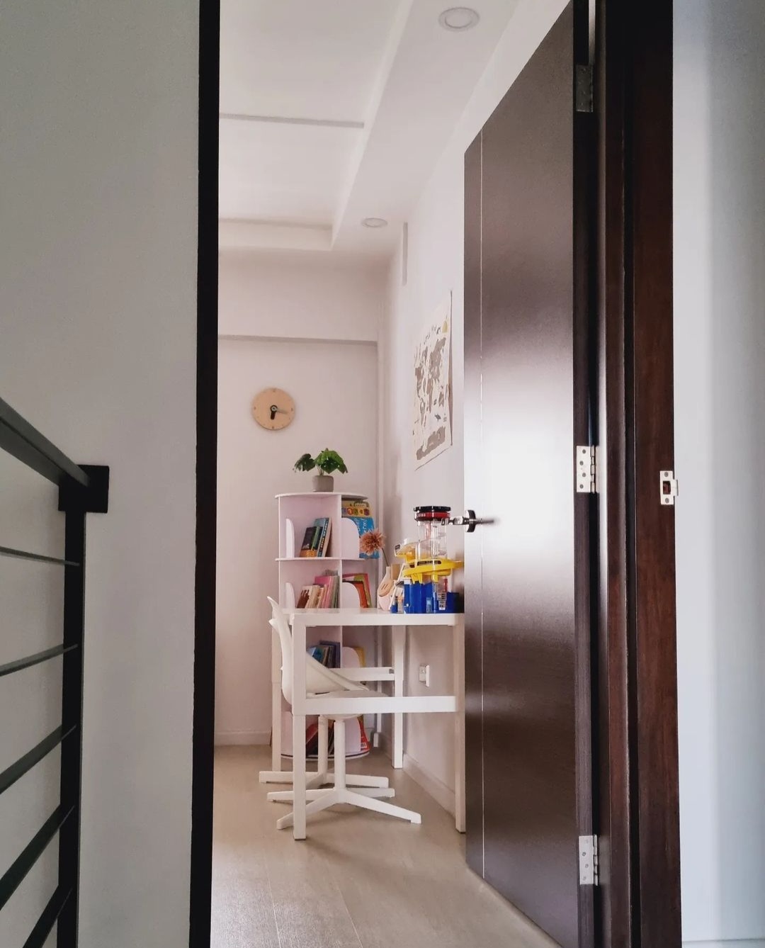 Kid's playroom! - White interior, modern hallway, wooden door, black railing, white shelving unit, colorful toys, potted