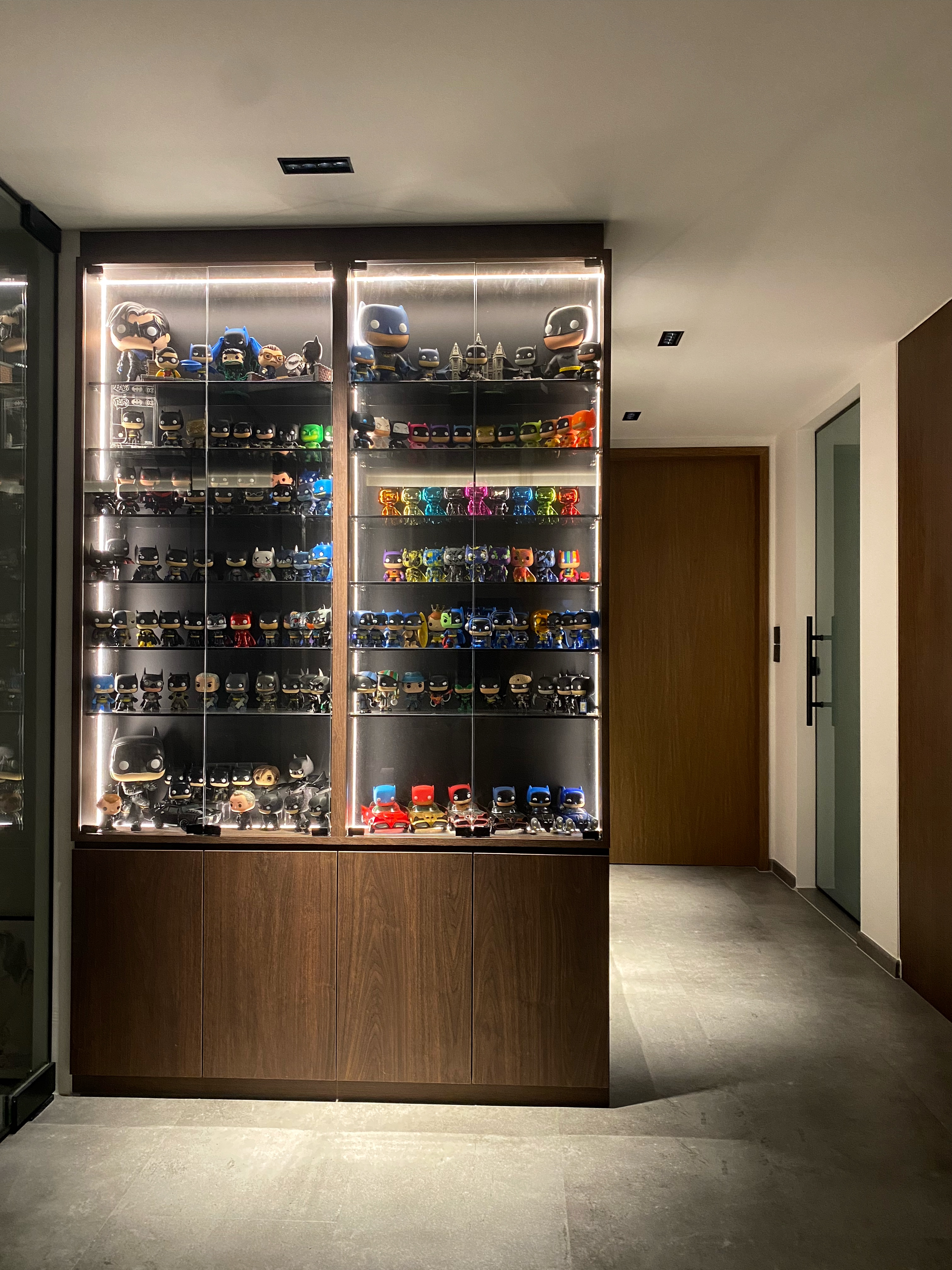 This is where the fun choice starts - Sleek modern display case filled with Batman action figures, Colorful Batman action