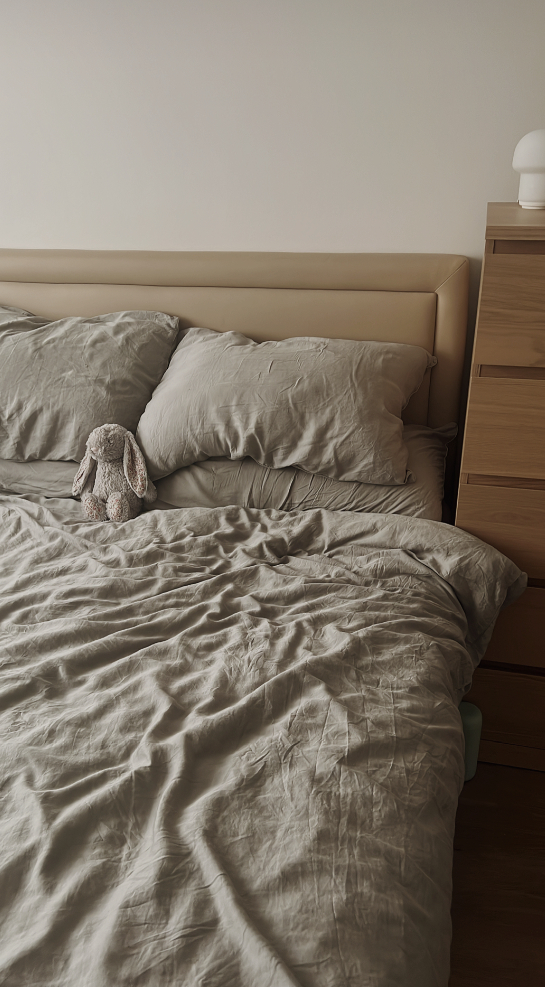 Creating our japandi home on a budget 🤎 - Soft, muted beige bedding, plush, light-colored stuffed bunny, wooden nightstand