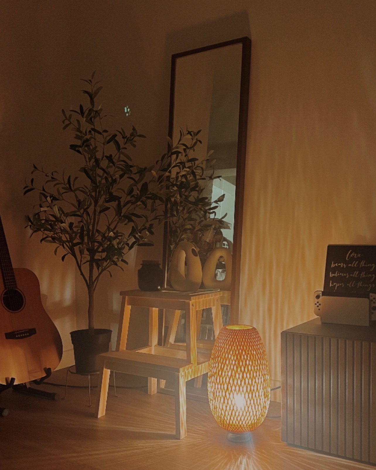 Creating our japandi home on a budget 🤎 - Warm, cozy, dimly lit room, wooden furniture, guitar leaning against wall, potted