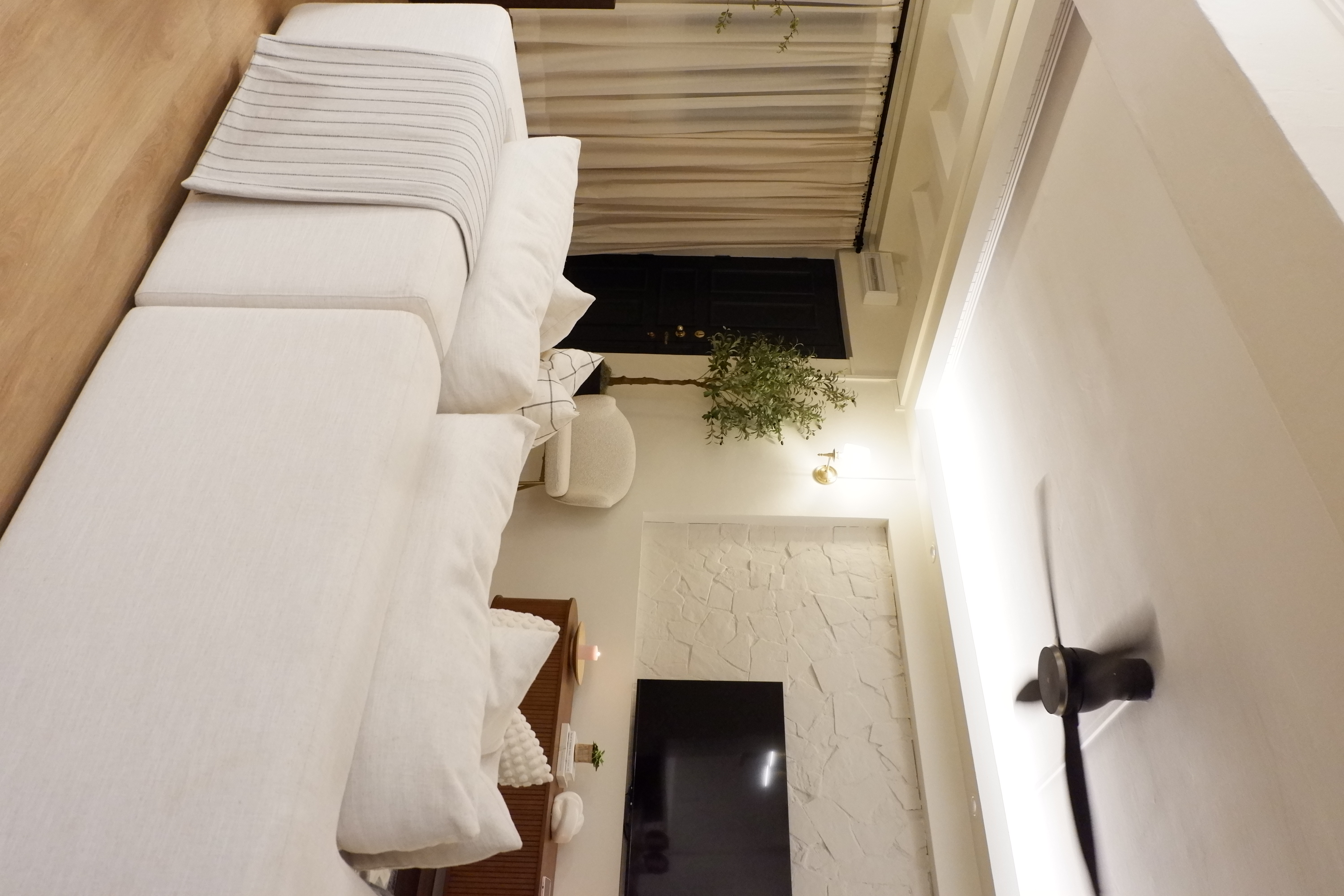 Upgrade outdated wall  - White sofa, beige cushions, striped pillows, wooden floor, modern decor, light fixture, black TV