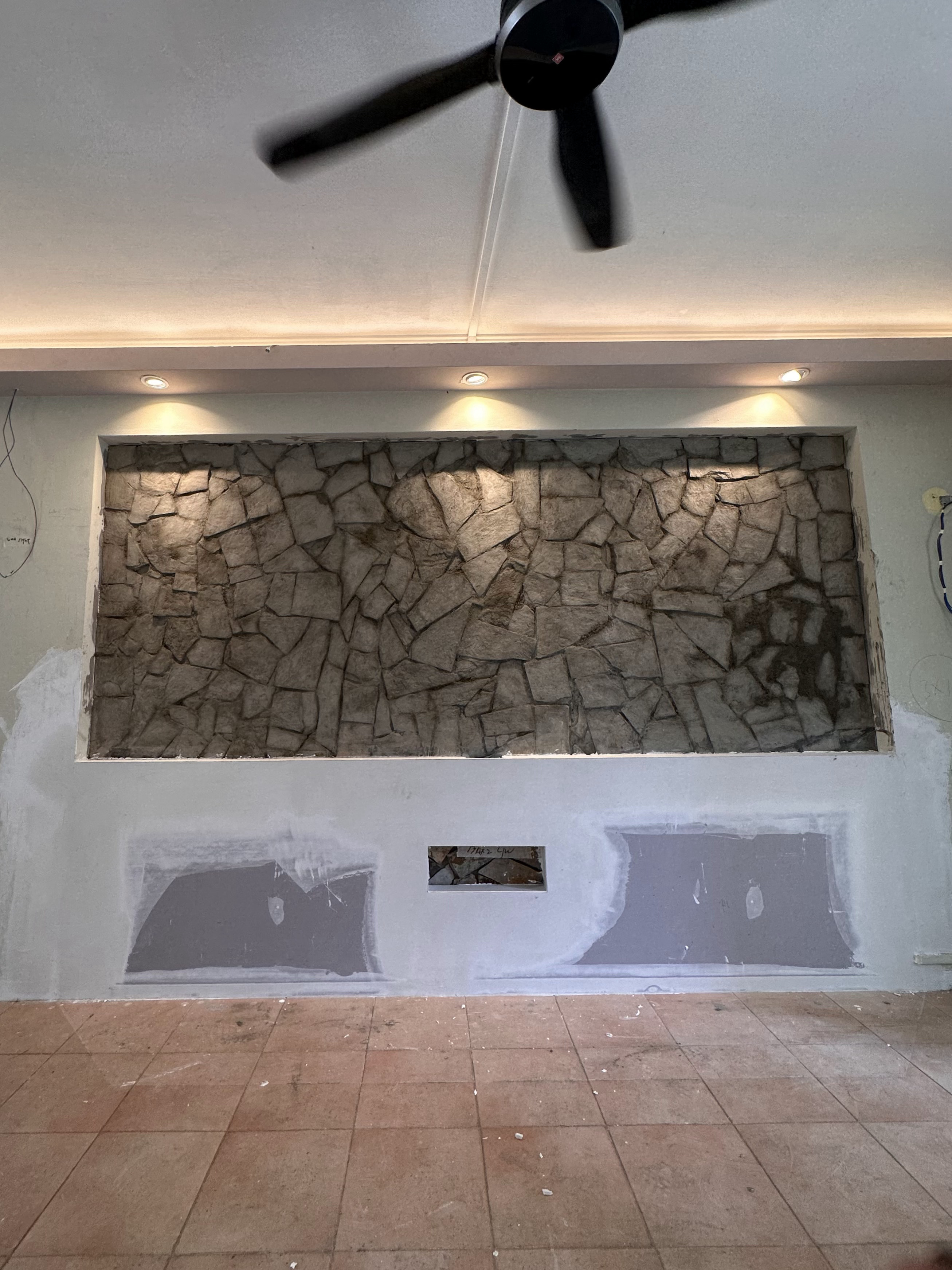 Upgrade outdated wall  - Stone wall with ceiling fan, under-construction room, unfinished walls, exposed plaster, unfinished