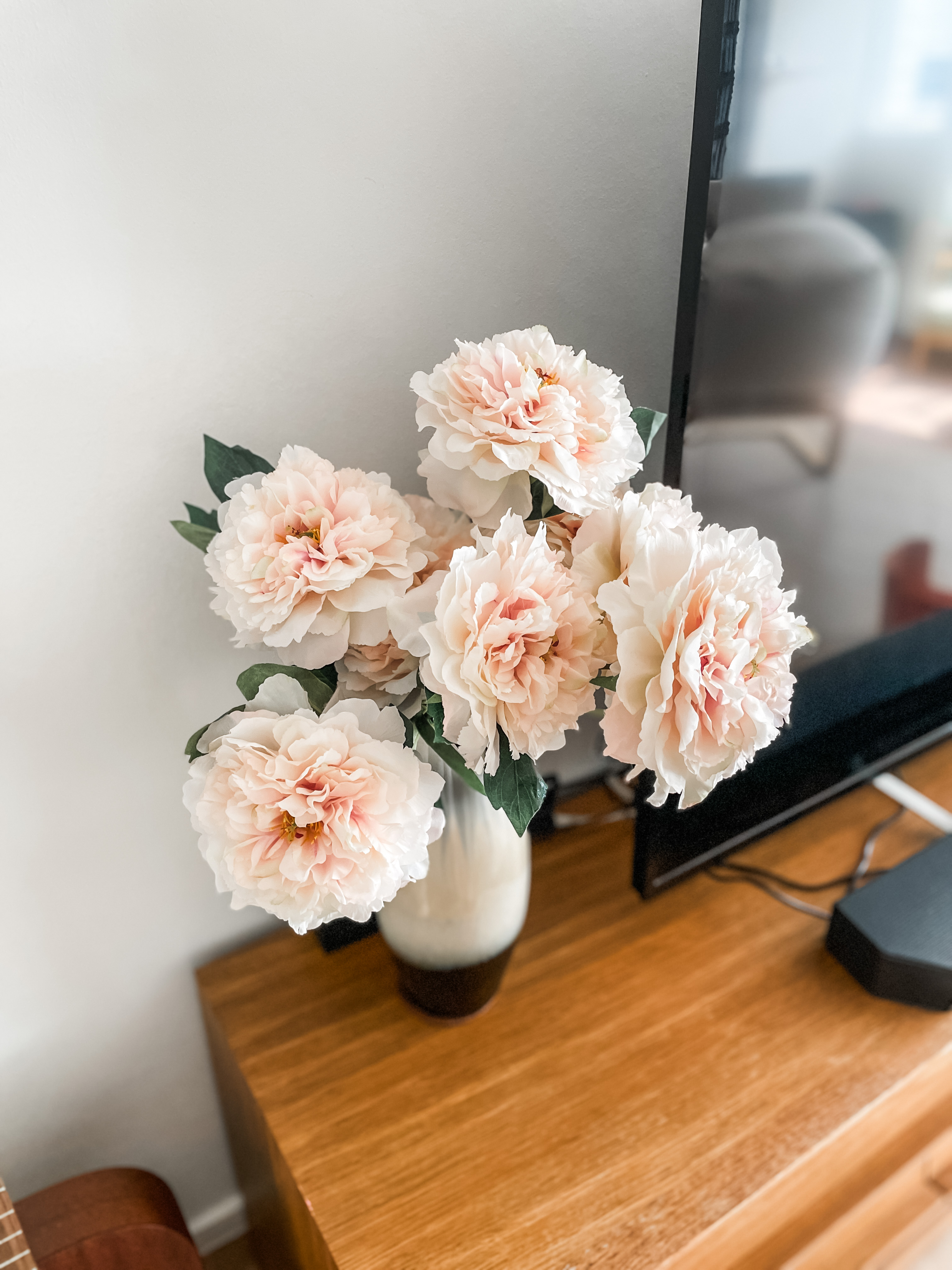 Step Into Our Snug & Soothing Living Space - Soft pastel pink and white peony flowers in a clear glass vase, placed on a