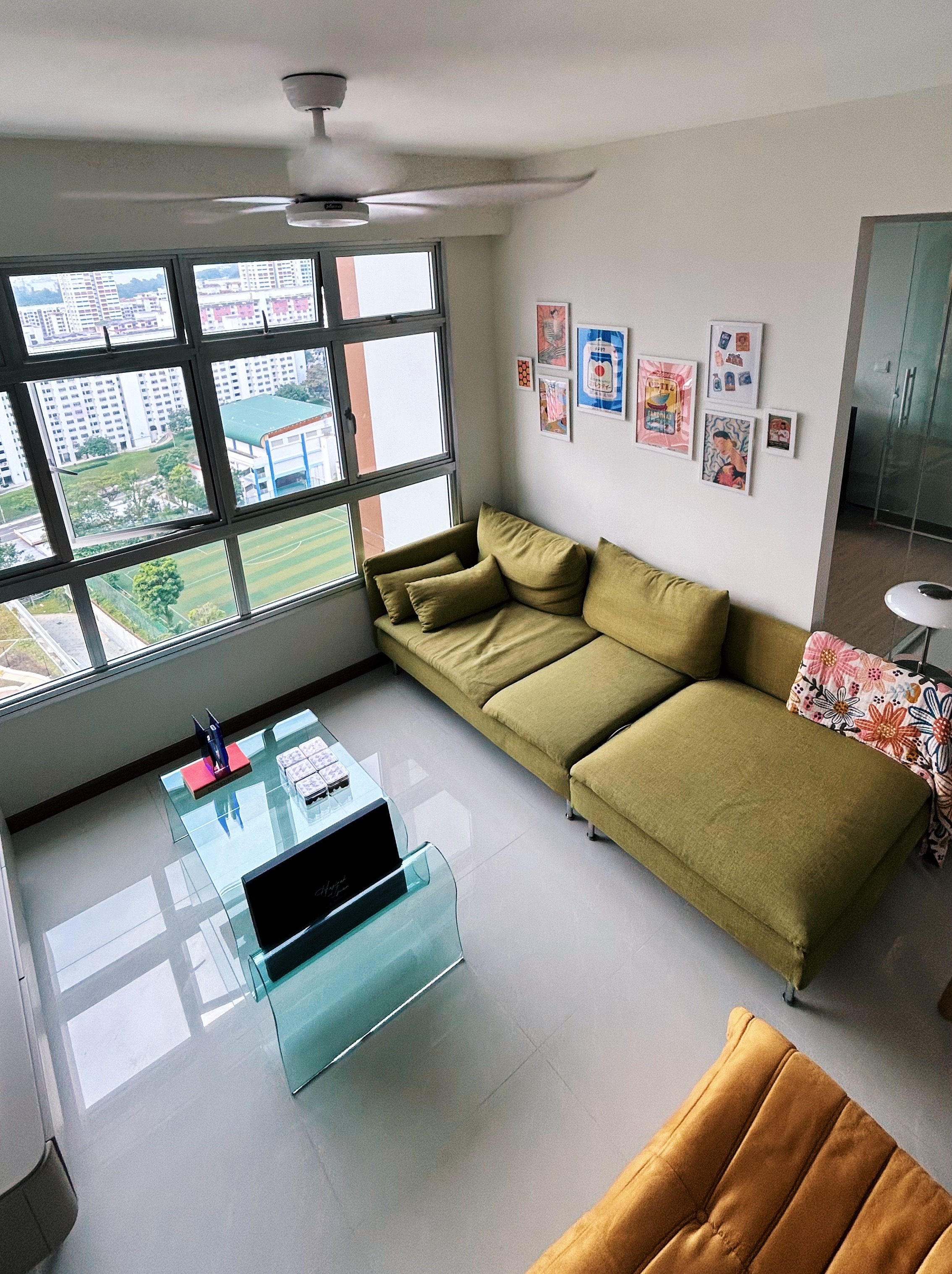 Creating our cosy and vibrant living room - Modern living room with large windows, green sofa, glass coffee table, colorful