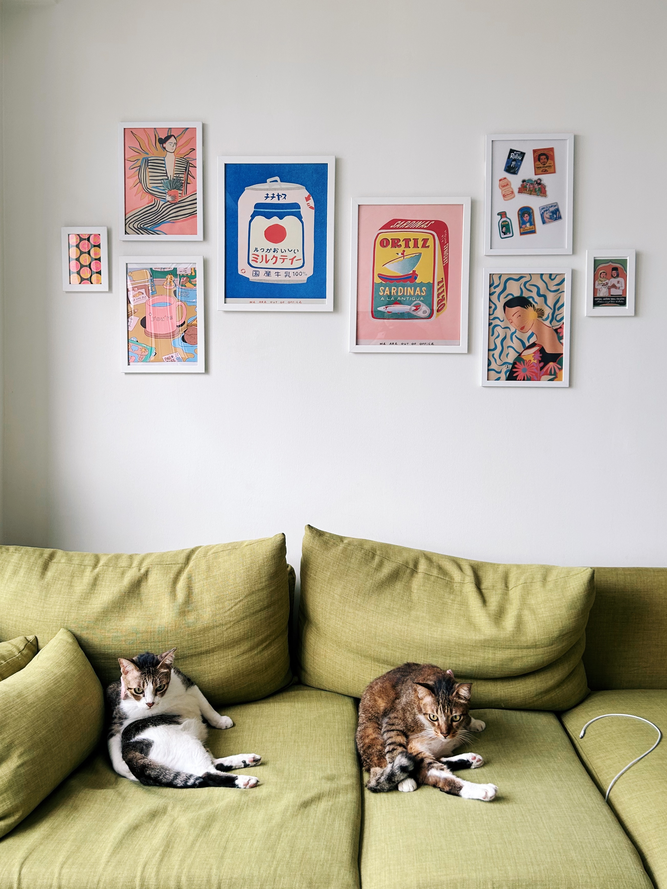 Creating our cosy and vibrant living room - Two cats lounging on a green couch in a modern living room, Wall art featuring