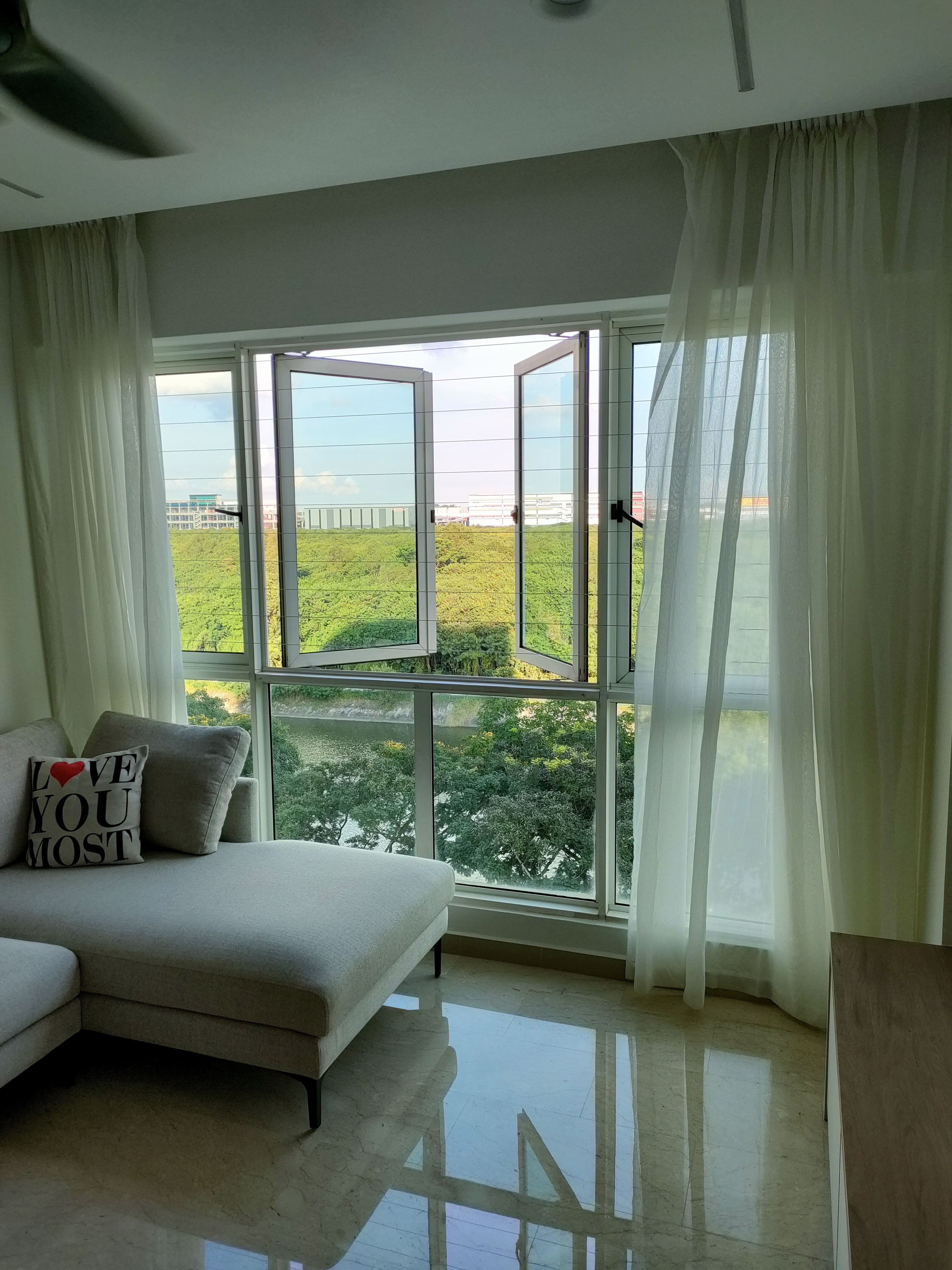 Living room where we gather for family bonding - Modern living room, large windows, natural light, outdoor view, greenery