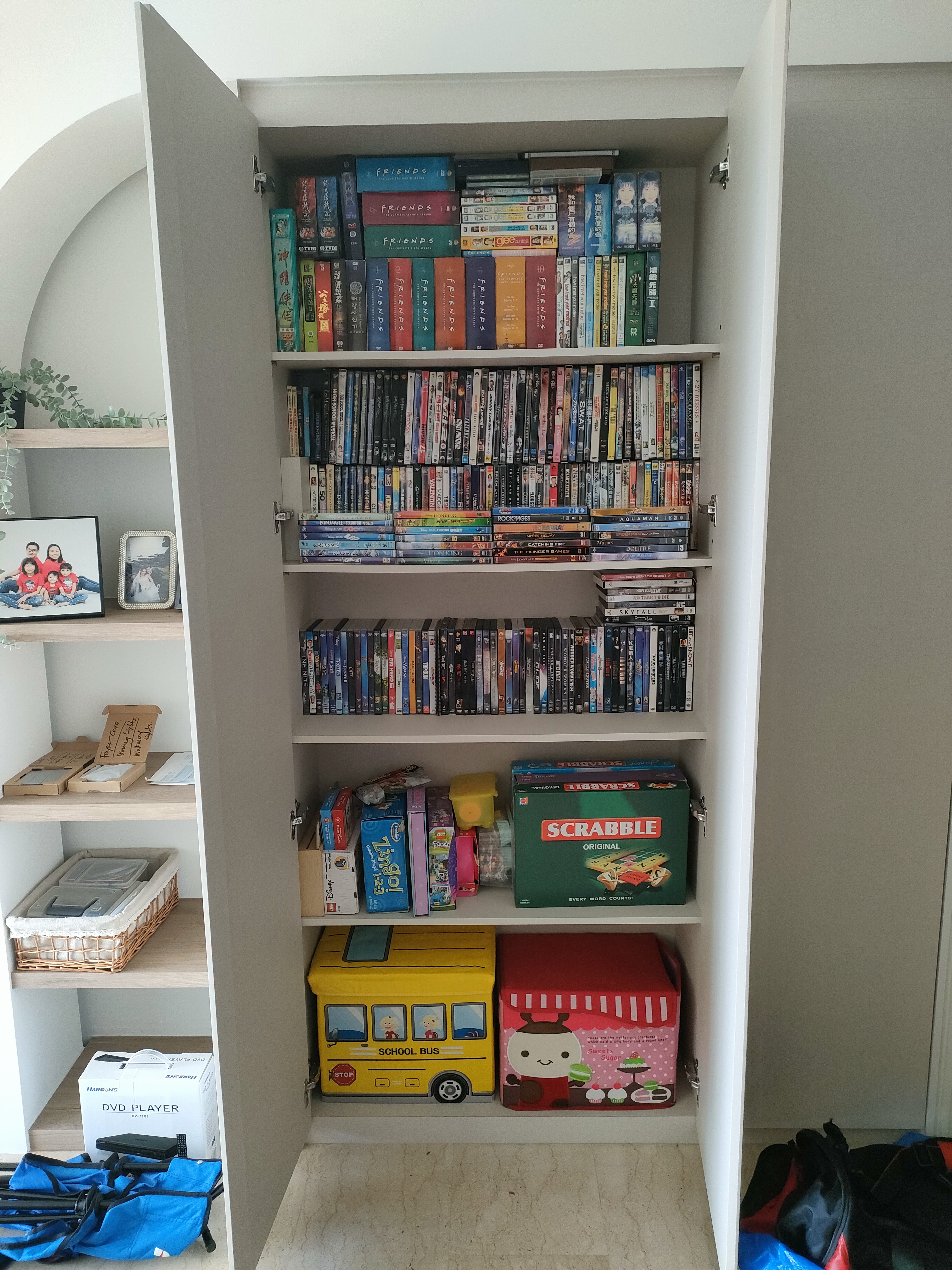 Living room where we gather for family bonding - Bookshelf filled with DVDs, board games, and puzzles, neatly organized