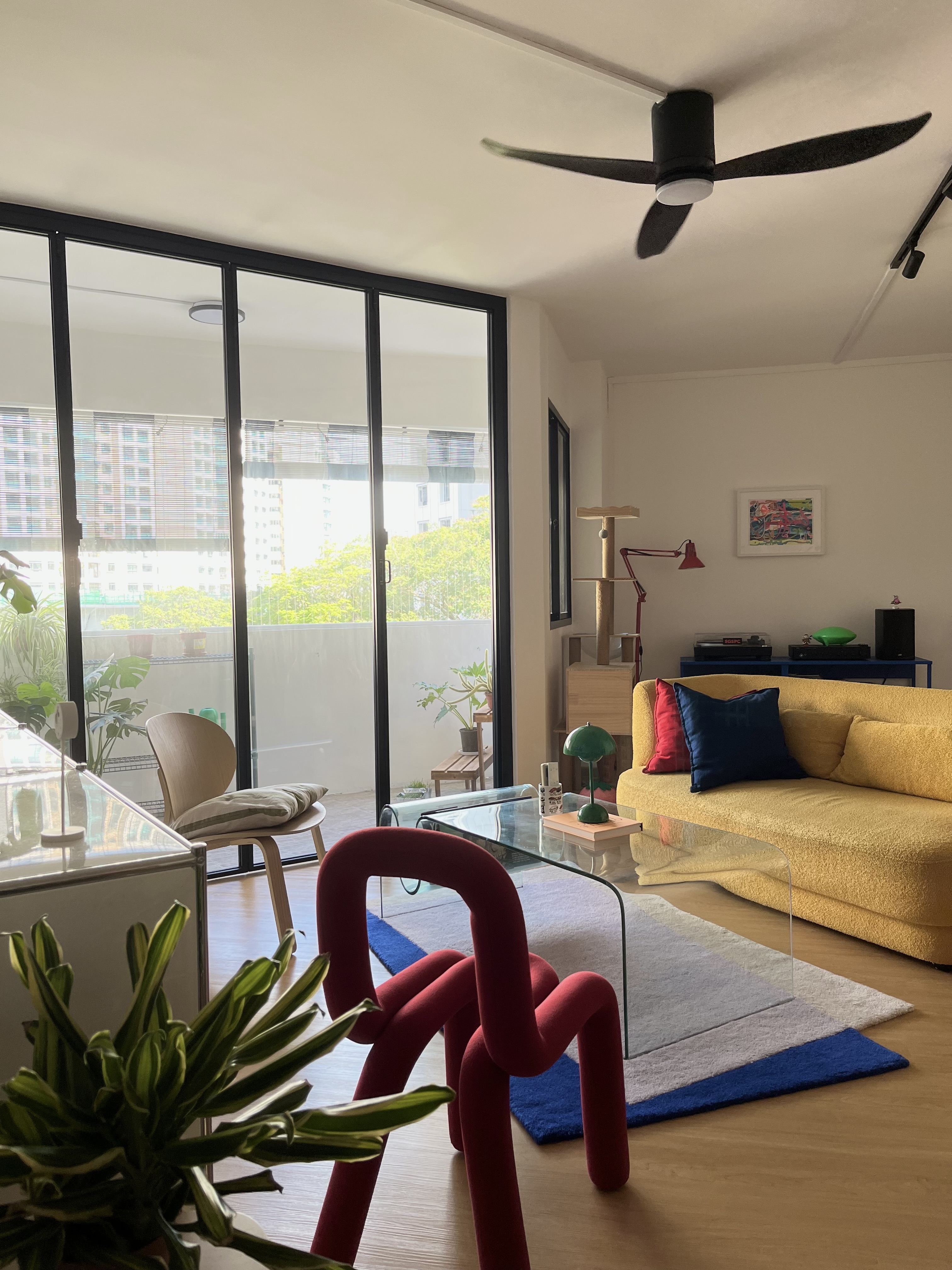 Living in Colours - Modern living room with large glass windows, contemporary furniture, yellow sofa, red and blue pillows