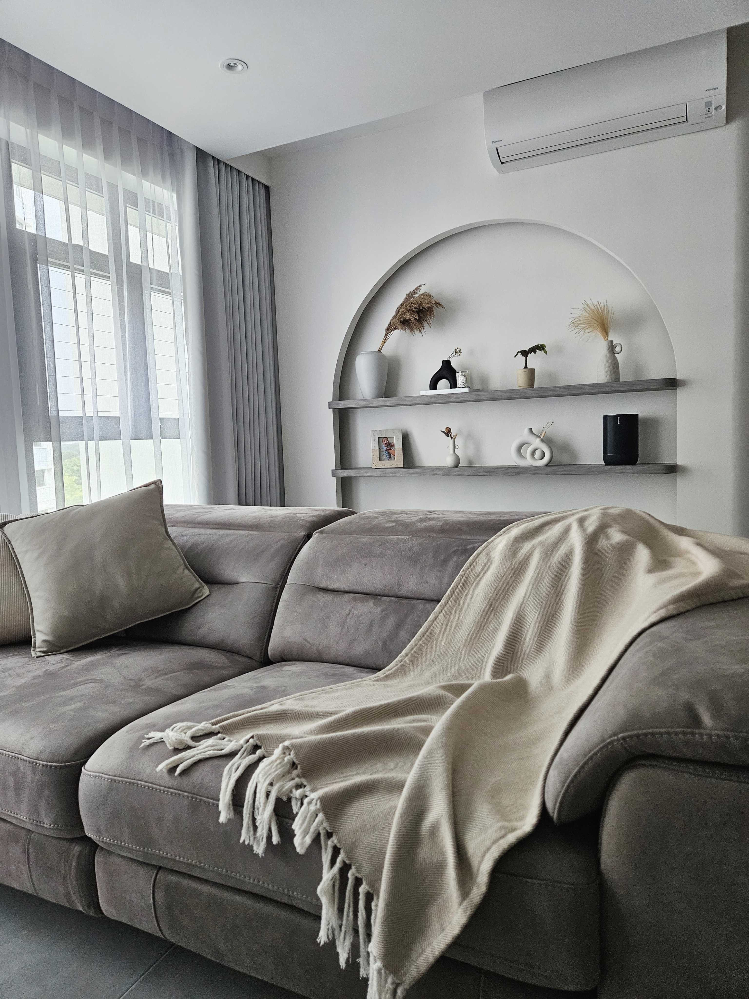 Clutter Free And Cozy Living Room - Grey sofa, beige throw blanket, modern decor, arched shelf, indoor plants, decorative