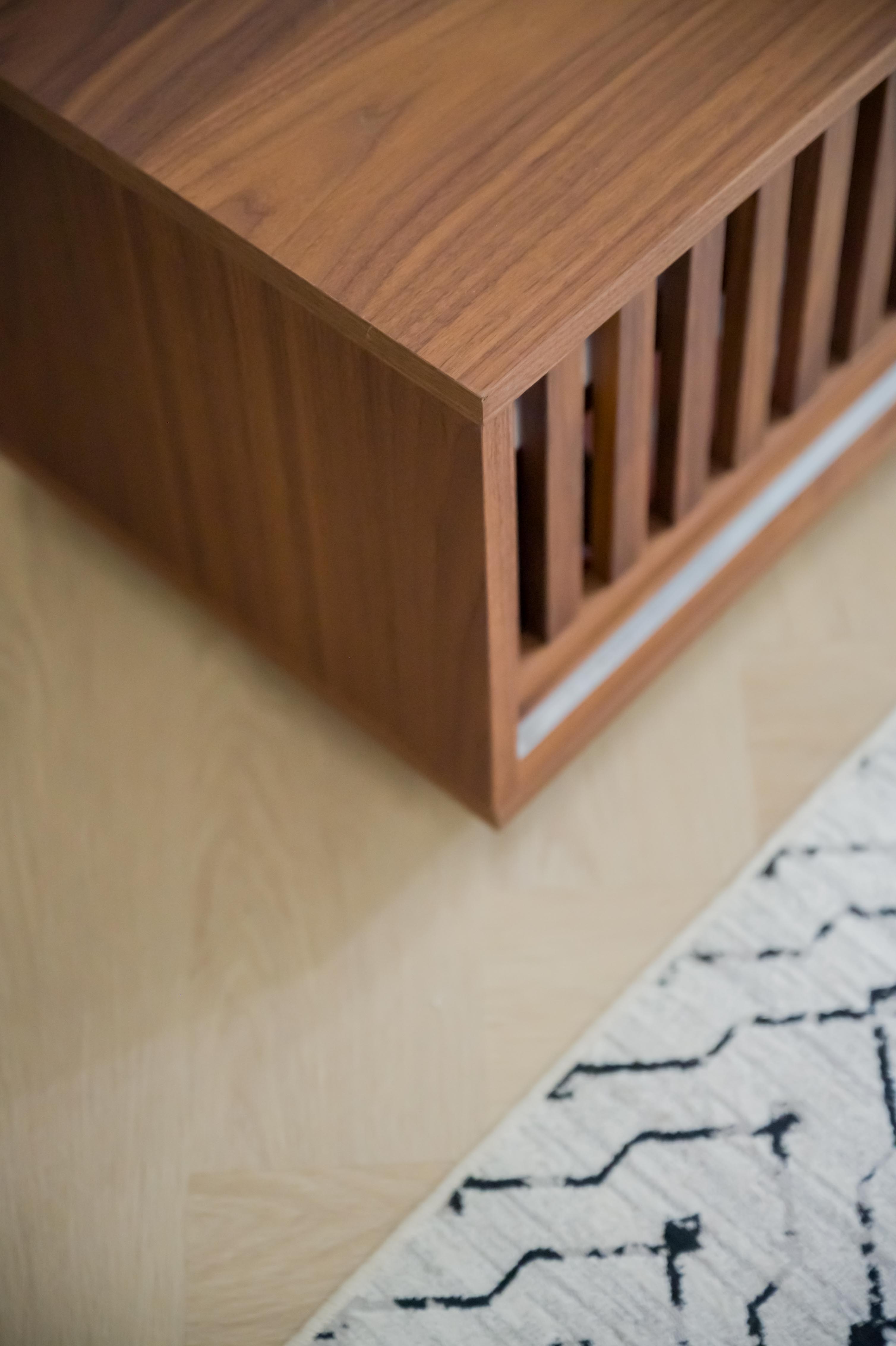 Minimal and clutter free living room - Wooden side table with vertical slats, light wooden floor, patterned rug beneath