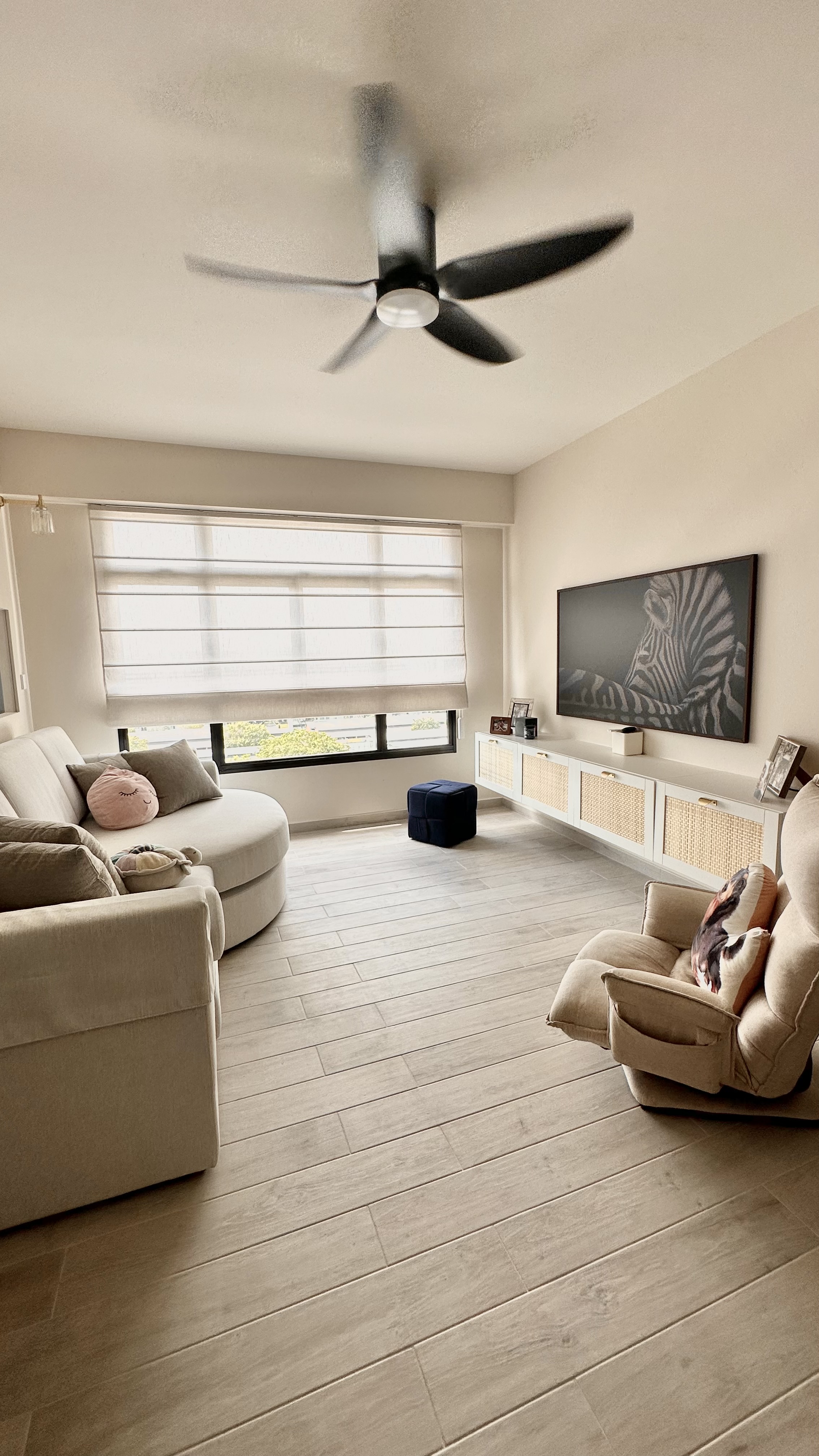 Self-styled Coastal Living Room (still a work in progress!)  - Cream-colored living room, modern ceiling fan, large window