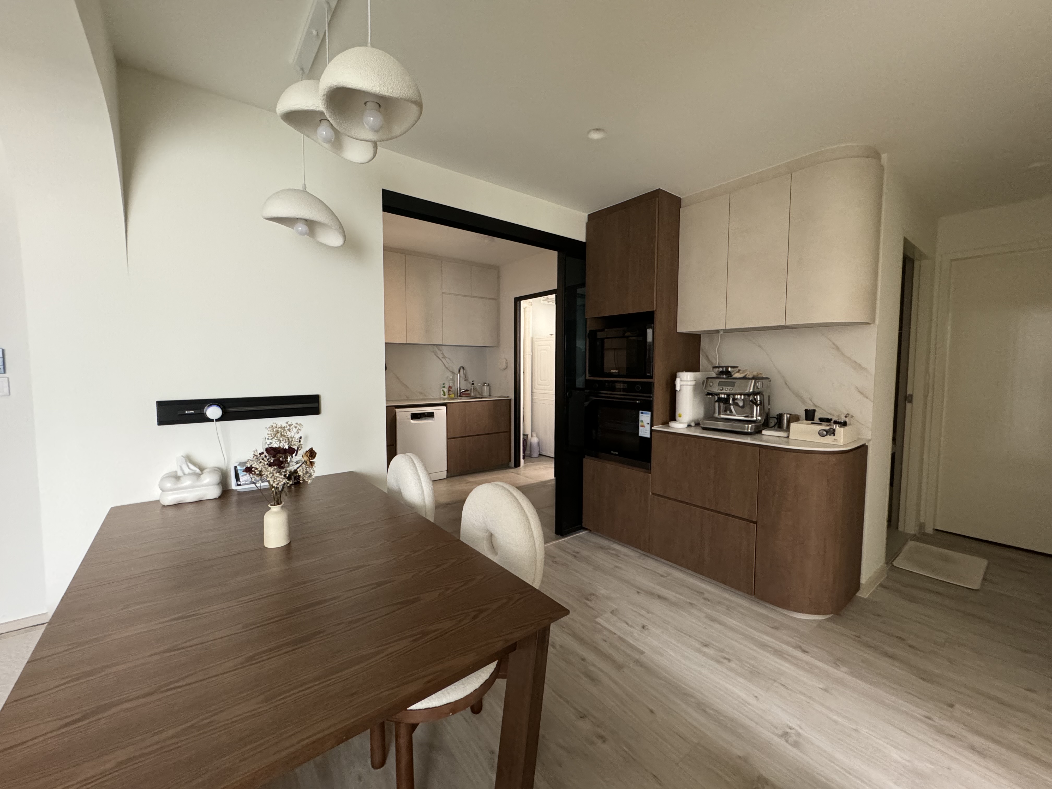 Buttercream Wabi Sabi Abode - Modern kitchen with minimalist design, wooden dining table, white chairs, pendant lights
