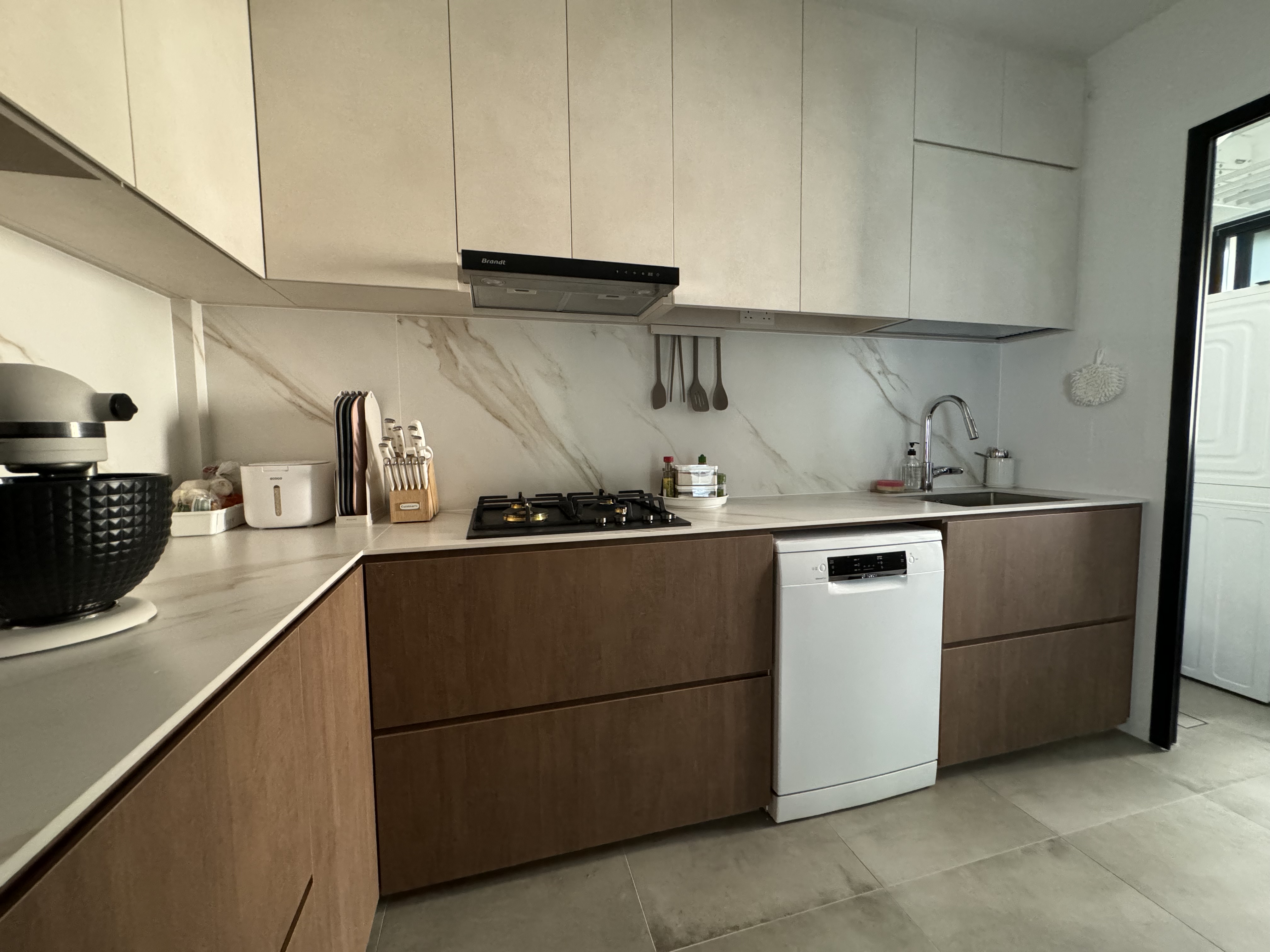 Buttercream Wabi Sabi Abode - Modern kitchen with sleek cabinetry, marble backsplash, under-cabinet lighting, stainless steel
