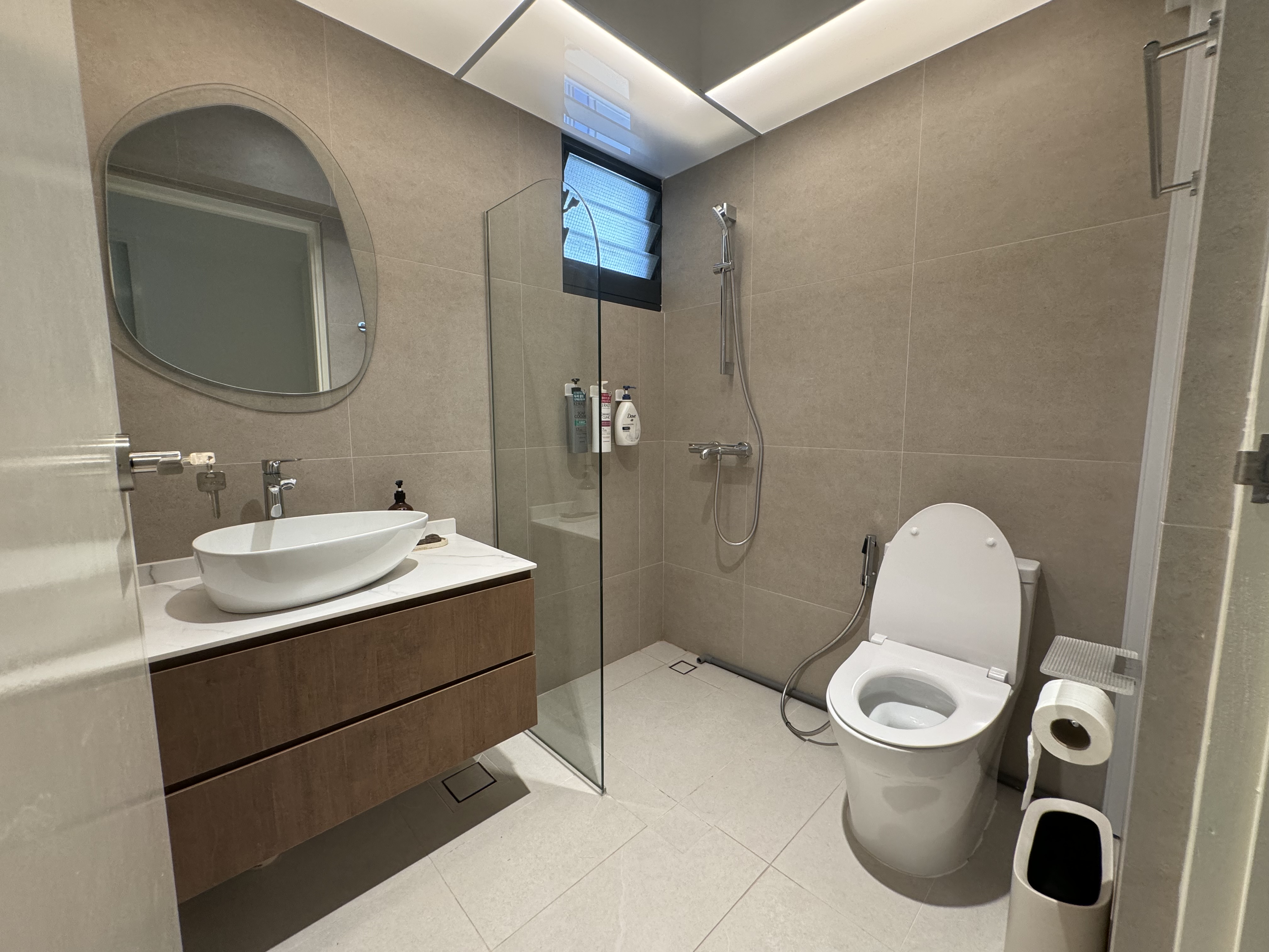 Buttercream Wabi Sabi Abode - Modern bathroom with sleek design, beige tiled walls and floor, large oval mirror, built-in