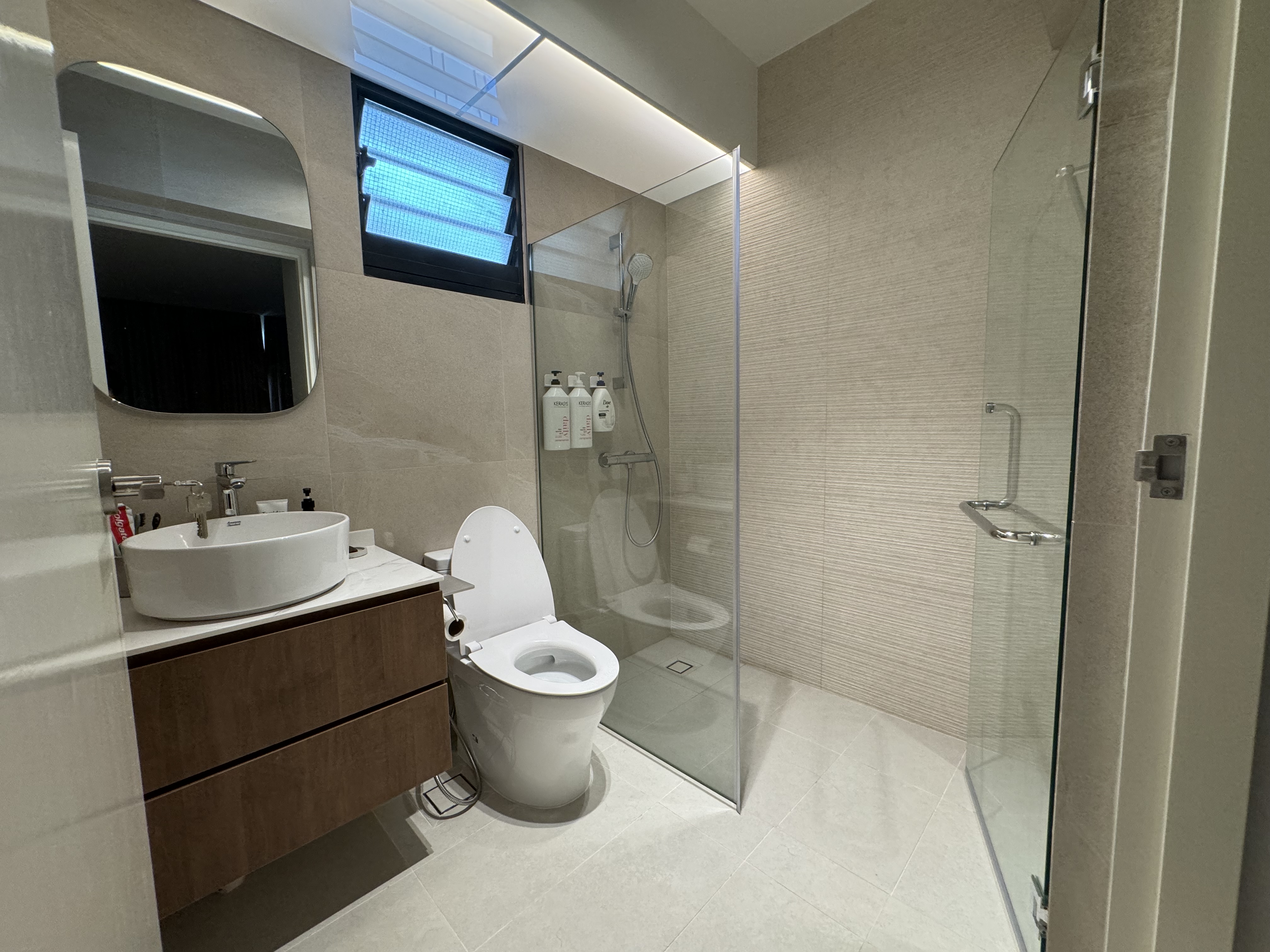 Buttercream Wabi Sabi Abode - Modern bathroom with sleek design, large mirror, white sink vanity, built-in toilet, glass