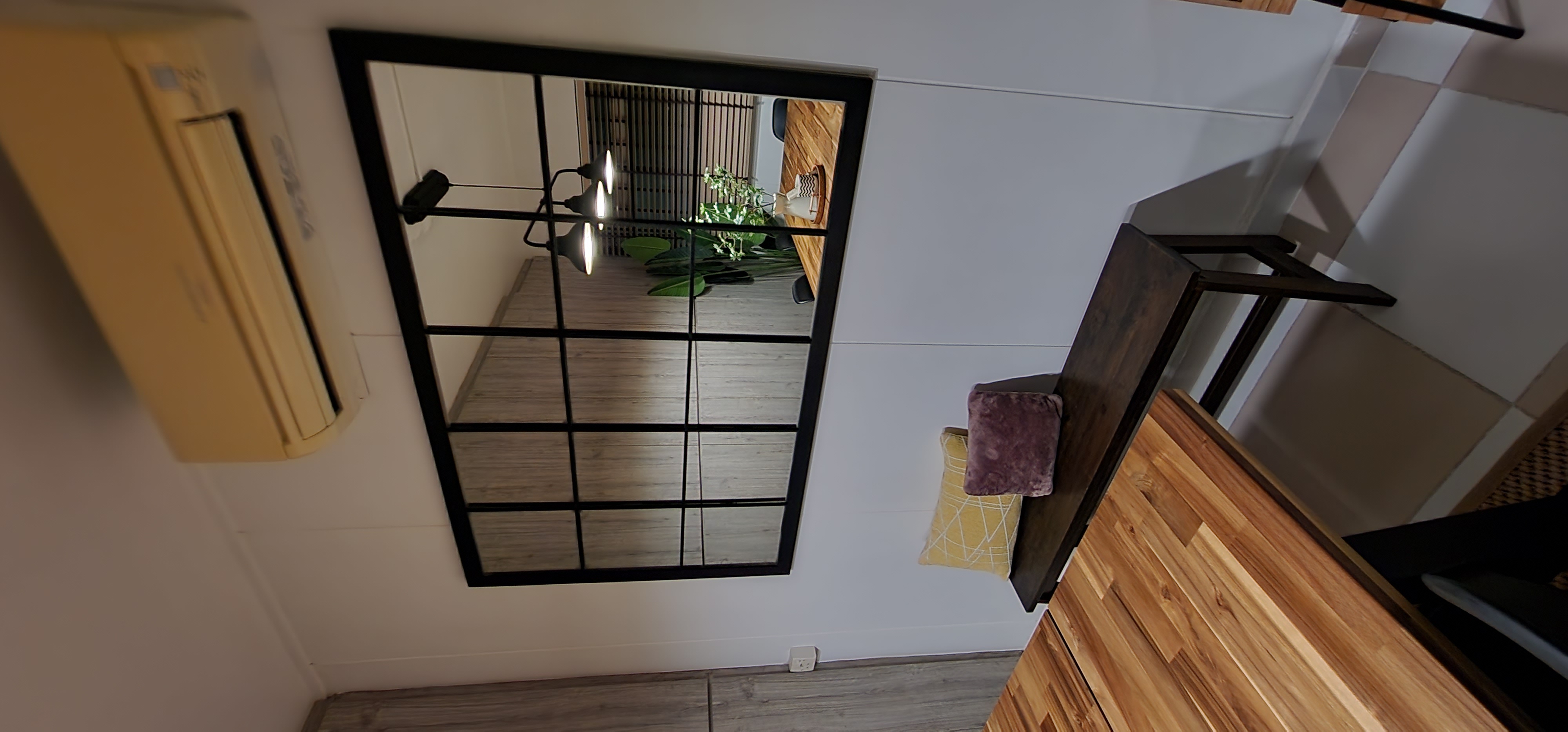 Multi-Functional Dining Room - Modern minimalist interior, wooden floor, black-framed mirror, yellow air conditioning unit