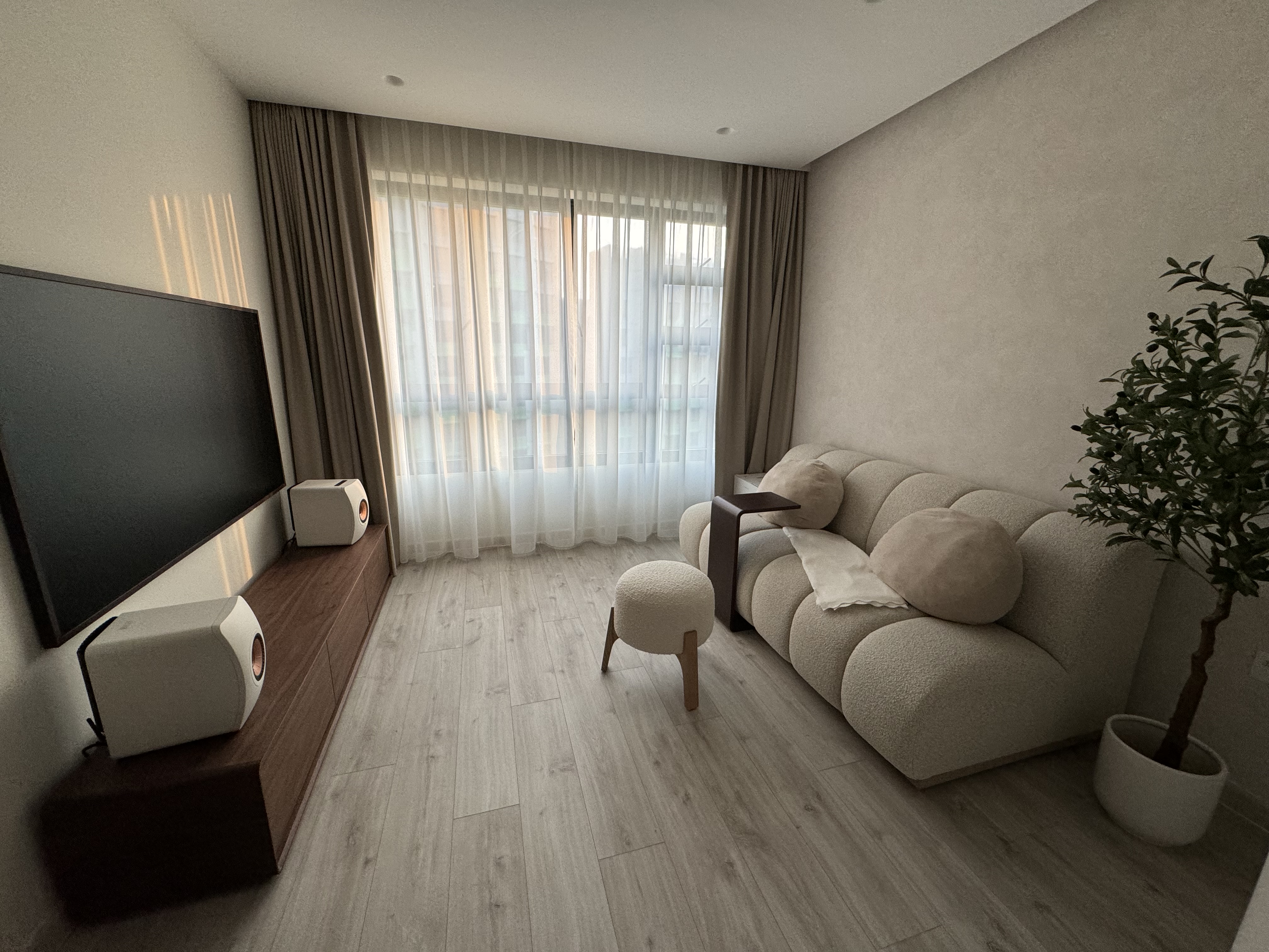 Love (our living room’s) curves & all (it’s) edges ❤️ - Large flat-screen TV, beige sofa, soft cushions, wooden side table