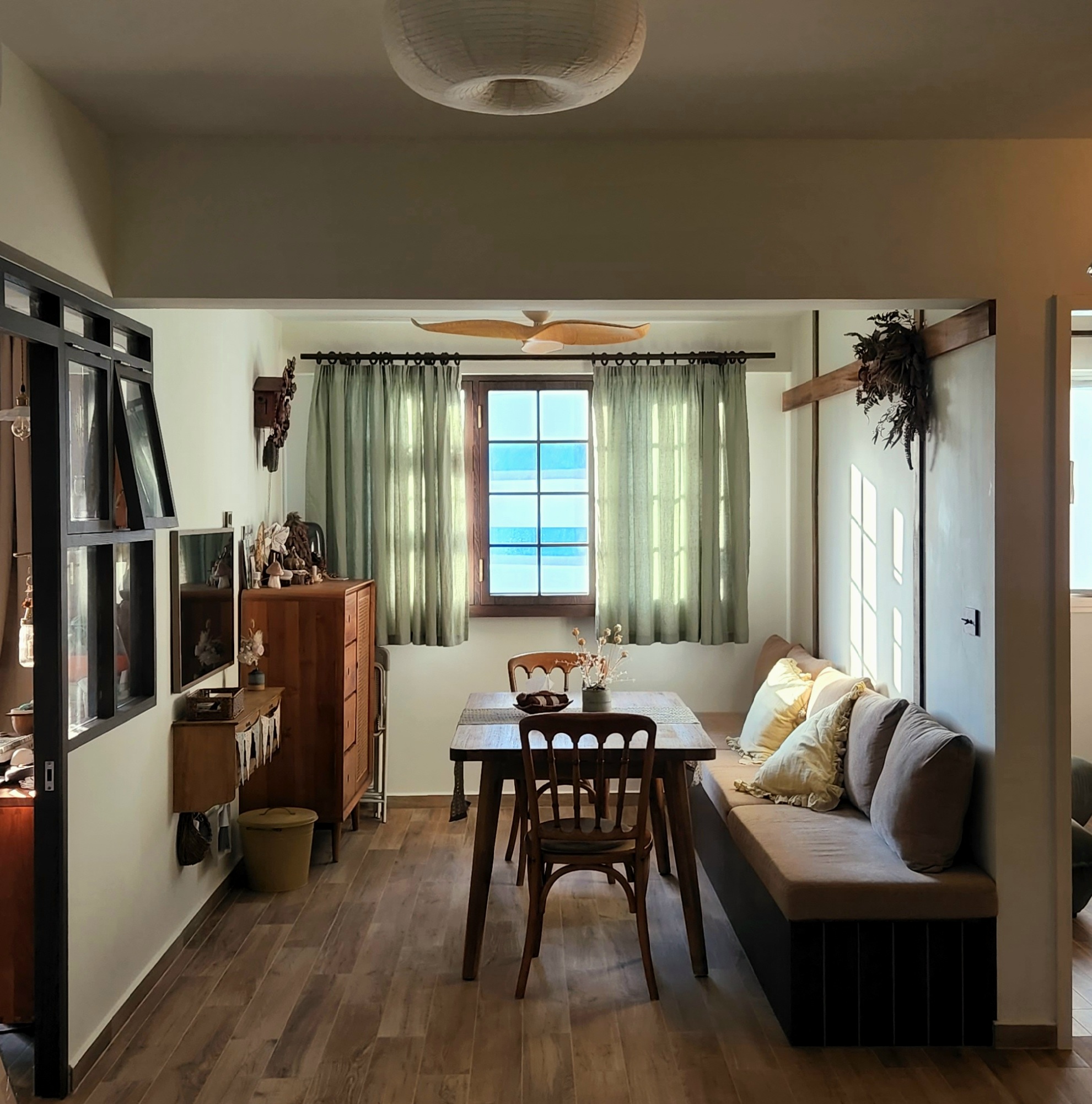 Gather here: Living and dining in the same space - Wooden dining table, beige sofa, green curtains, wooden cabinet