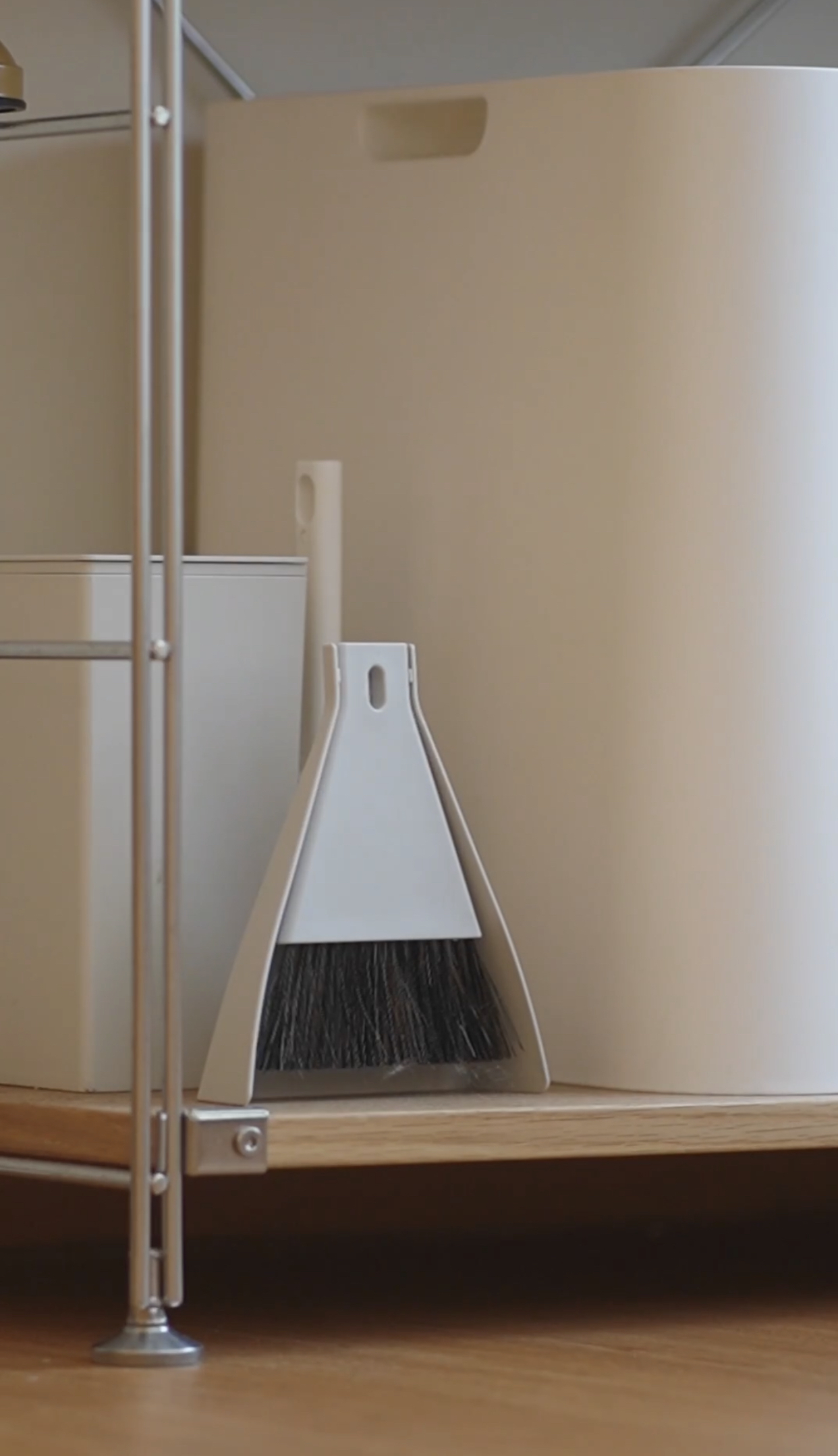 Muji Cleaning and Organization Tools: Simple and effective - White dustpan, white broom, wooden shelf, beige wall, minimalist