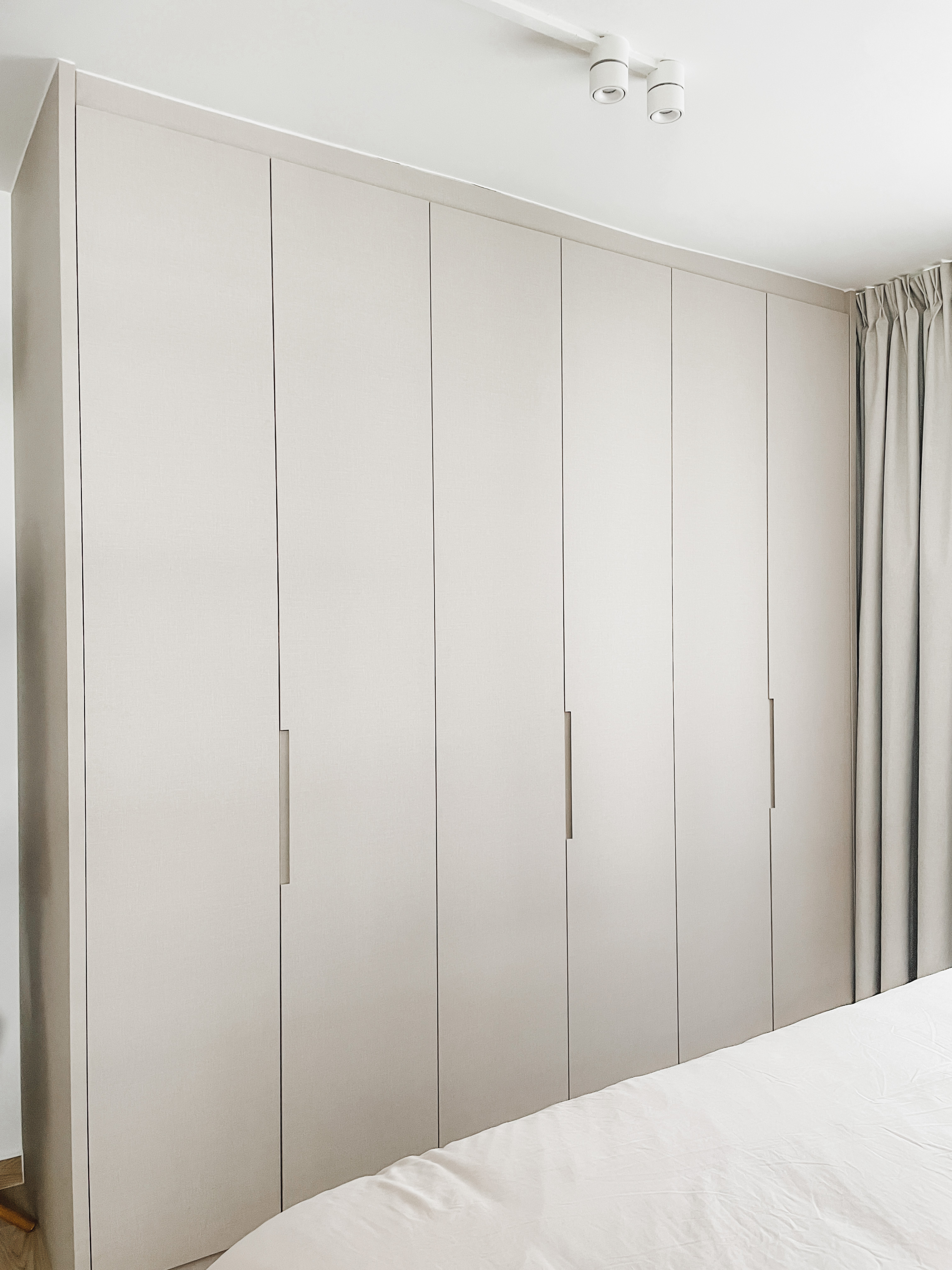 Our Master Bedroom: A Restful Retreat  - Light-colored, minimalist wardrobe with sleek doors, modern design, neutral color
