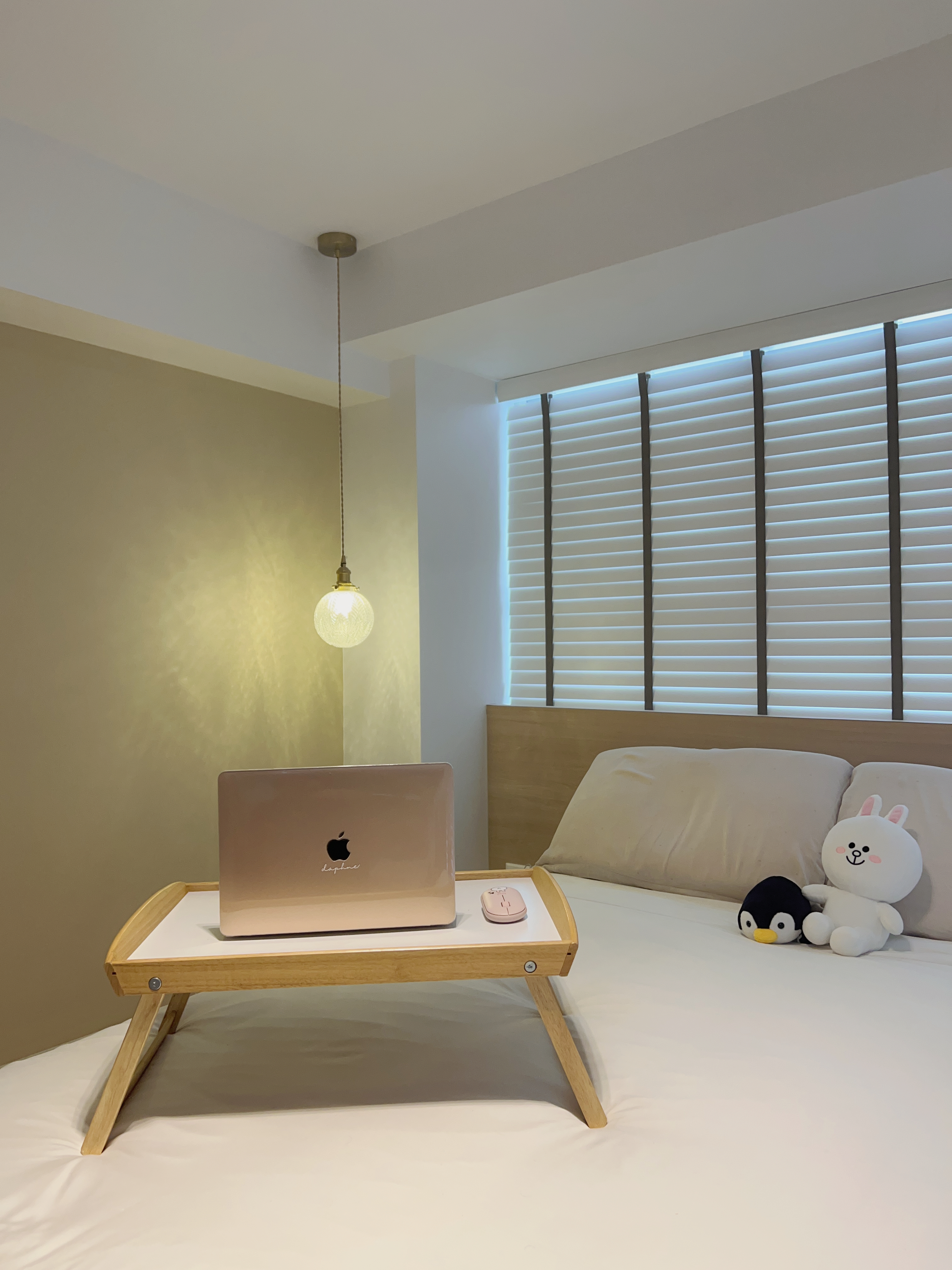 Maximising Bay Windows to Create A Cozy & Functional Master Bedroom - Laptop on wooden tray, beige wall, soft lighting